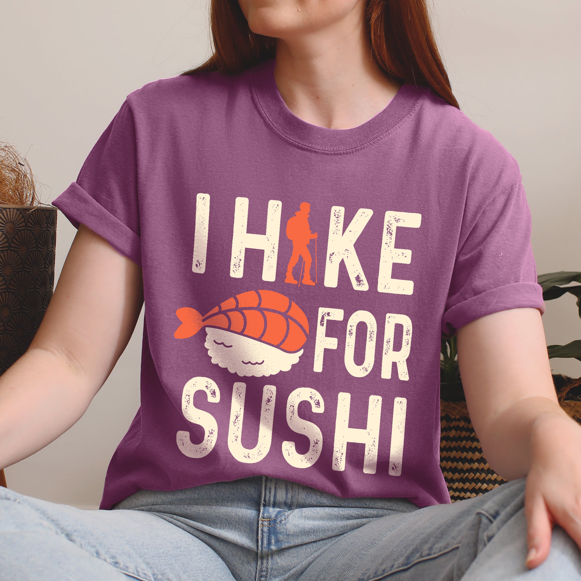 Berry (Dark Violet) graphic t-shirt with 'I Hike for Sushi' text in cream lettering featuring orange hiker silhouette and sushi nigiri illustration with orange fish and white rice