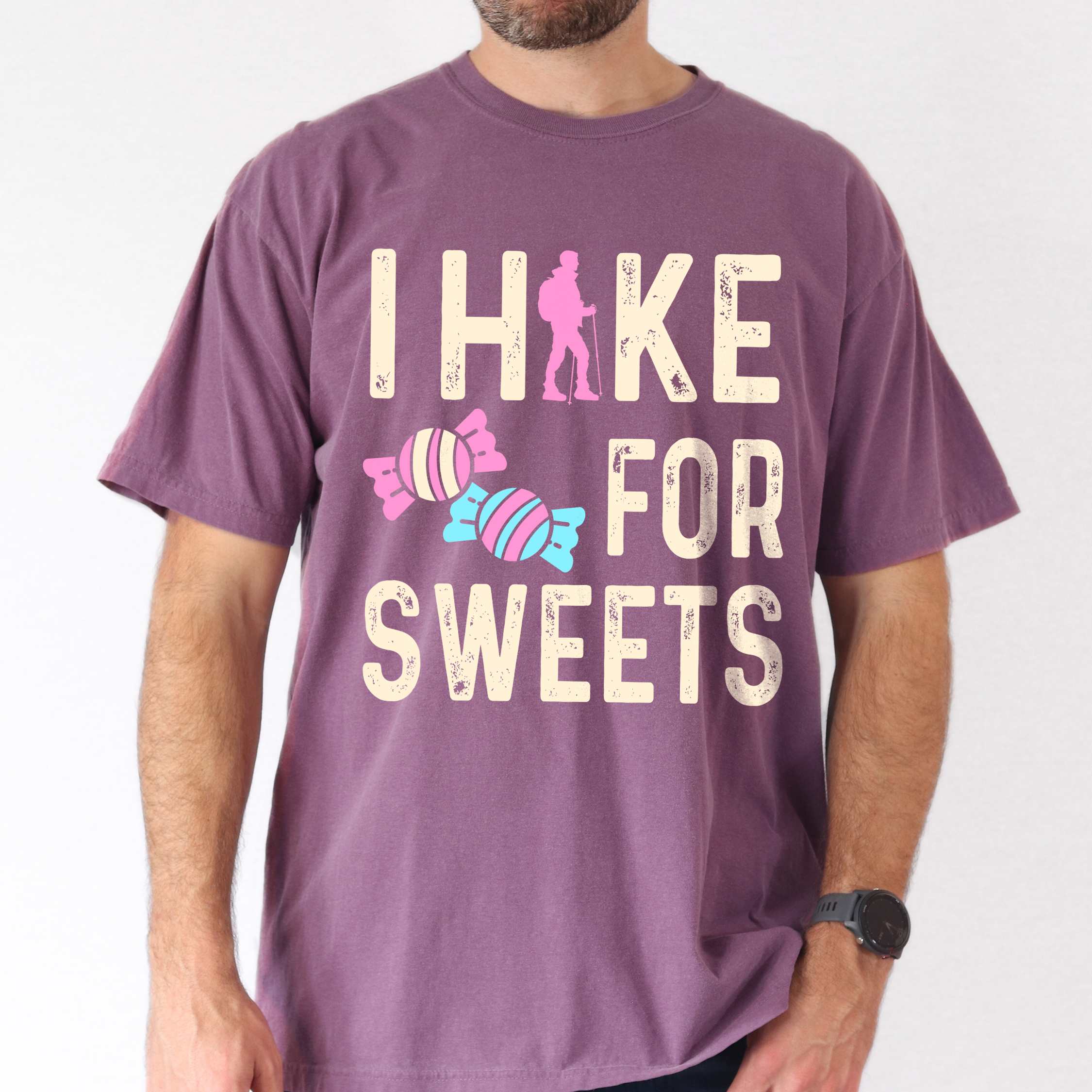 Man wearing berry 'I Hike for Sweets' text in cream lettering, illustrated pieces of candies, and backpacker for candy lovers