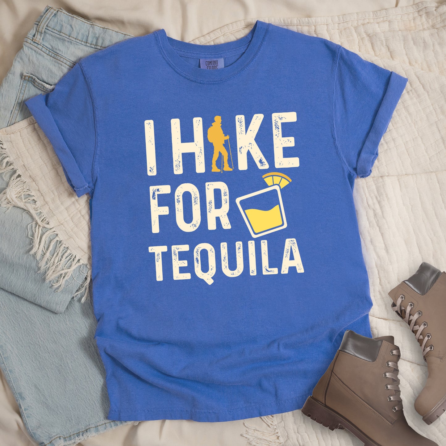 Flo Blue (Bright Blue) in flatlay graphic t-shirt with 'I Hike for Tequila' text in cream lettering featuring orange hiker silhouette and tequila shot glass illustration with lime garnish