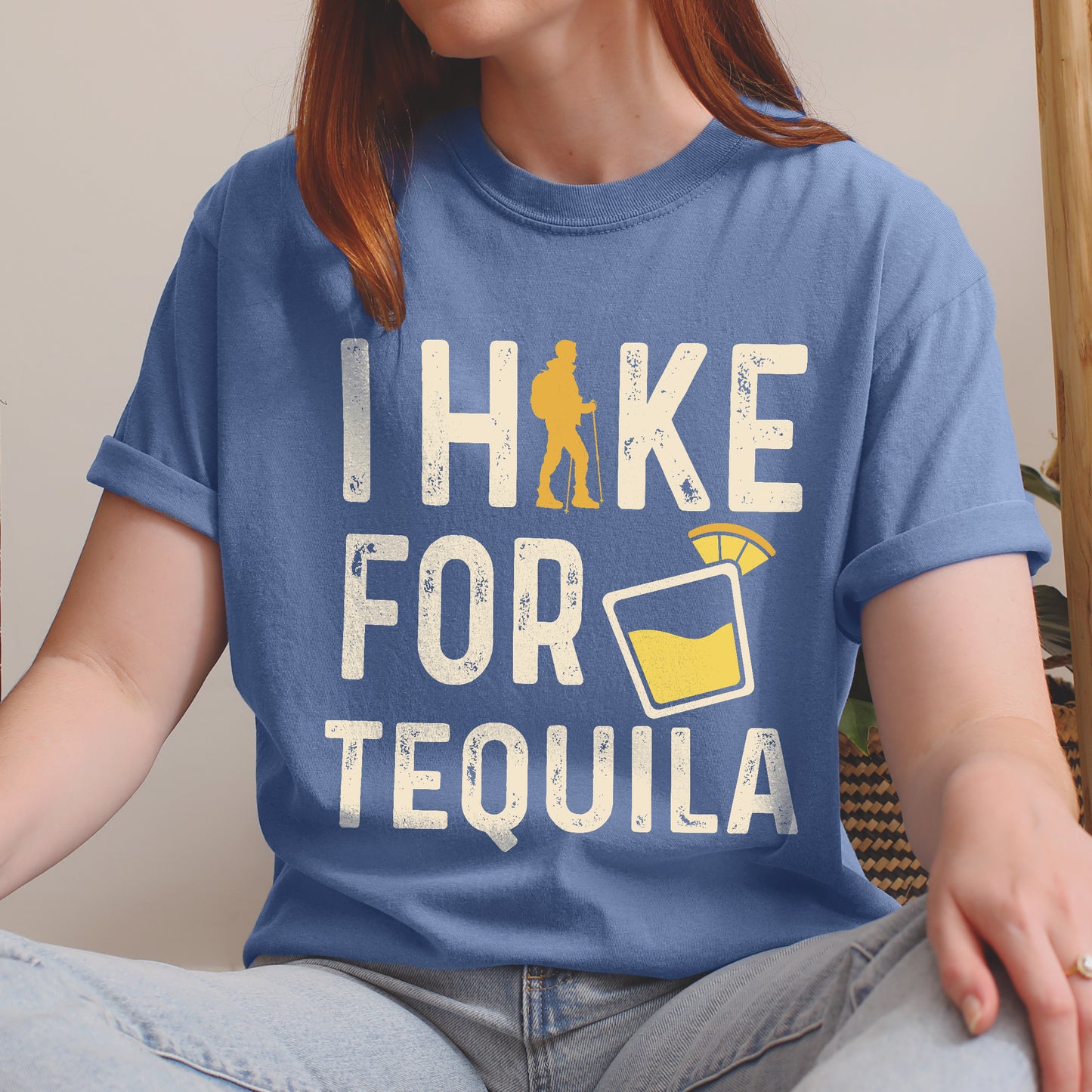 Blue Jean (Denim Blue) graphic t-shirt with 'I Hike for Tequila' text in cream lettering featuring orange hiker silhouette and tequila shot glass illustration with lime garnish
