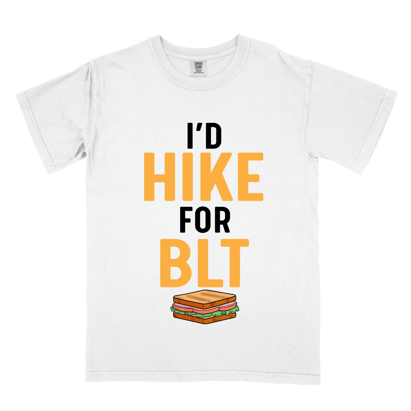 White t-shirt with text "I'D HIKE FOR BLT". The words "I'D" appear in black at the top, "HIKE" in large gold/yellow letters in the middle, "FOR" in black, and "BLT" in matching gold/yellow at the bottom. Below the text is a colorful illustration of a BLT sandwich showing toast, maybe bacon, lettuce, and tomato layers. The simple, bold design emphasizes hiking motivation through food rewards.