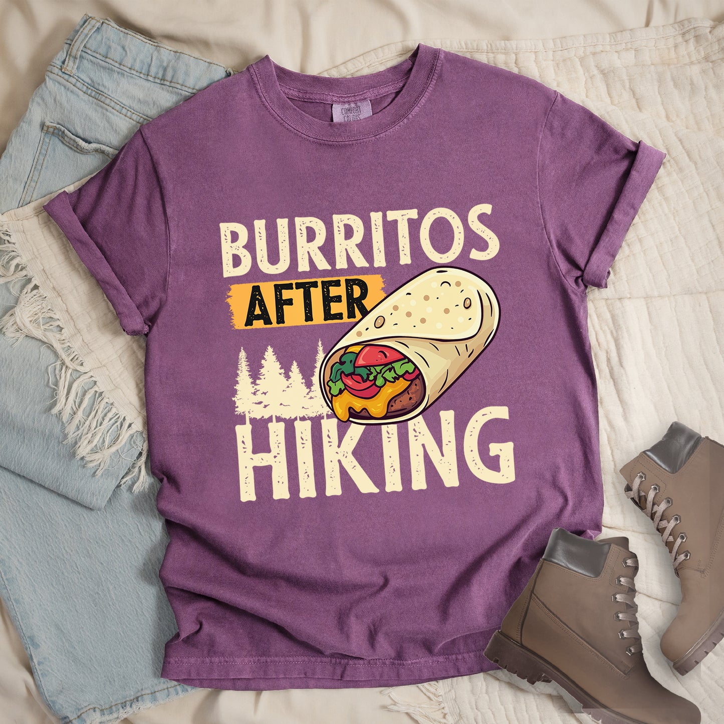 Berry (Dark Violet) t-shirt with distressed text reading "BURRITOS AFTER HIKING". "BURRITOS" appears at the top in cream/off-white letters, "AFTER" in black text on an orange background in the middle, and "HIKING" in matching cream letters at the bottom. Between the text is an illustration of a burrito with visible fillings (beans, cheese, lettuce, tomato) and pine tree silhouettes in cream color. The design has a vintage, weathered appearance.