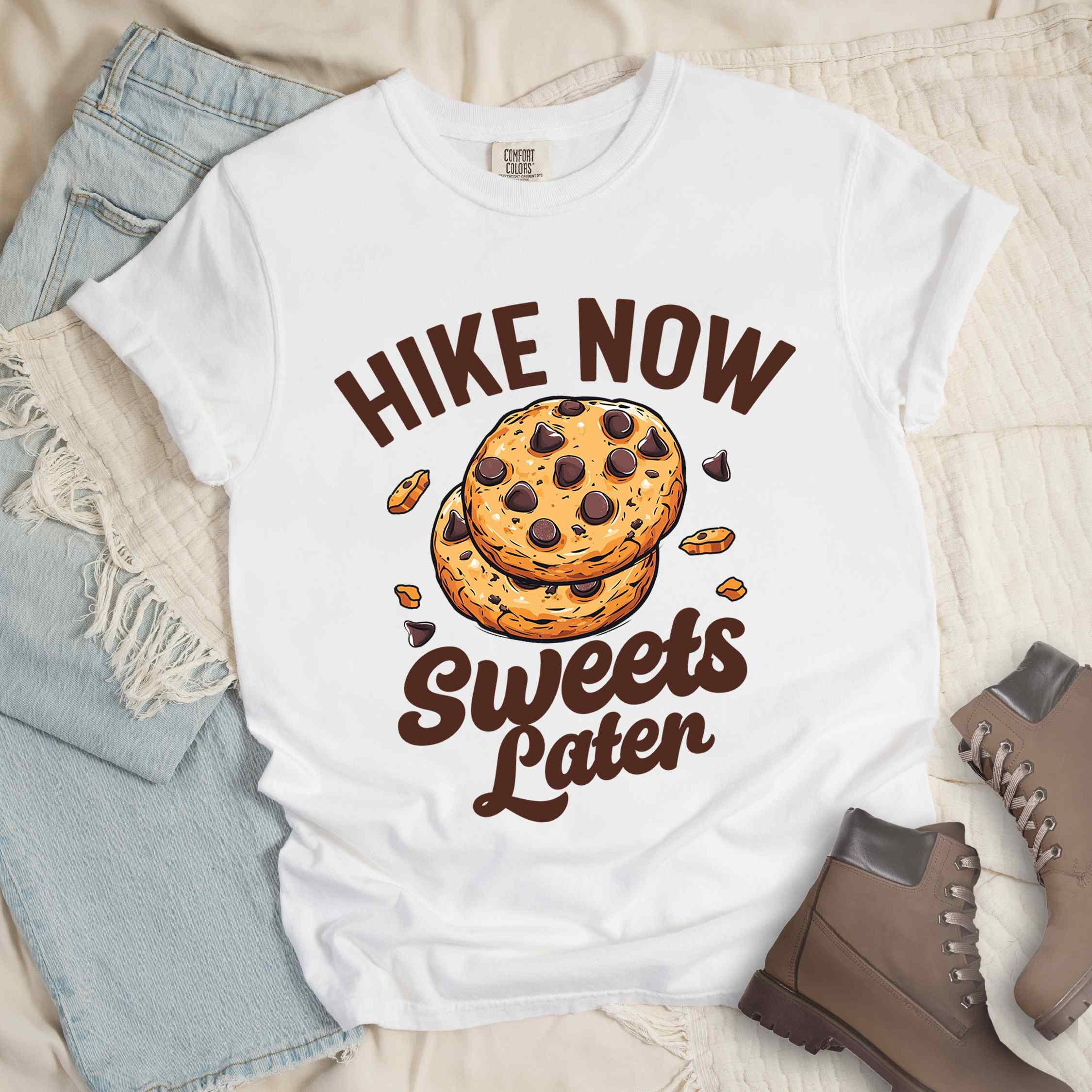 White “Hike Now Sweets Later” colored vintage tee with bold and script typography, illustration of chocolate chip cookies with crumbs scattered around. Perfect for cookie lovers.