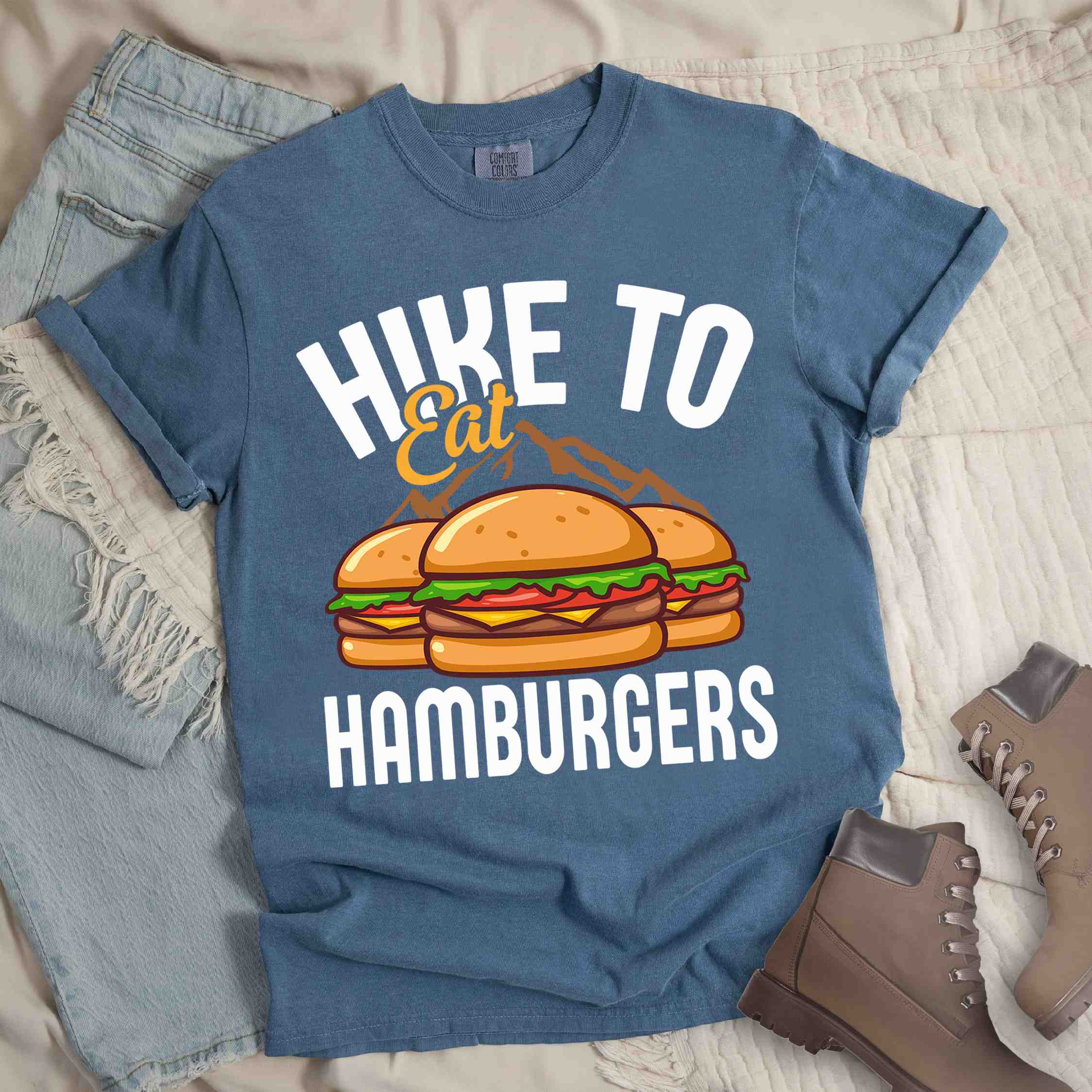 Blue jean "Hike to Eat Hamburgers" colored vintage tee with bold typography, illustrated juicy hamburger, and backpacker for burger enthusiasts.