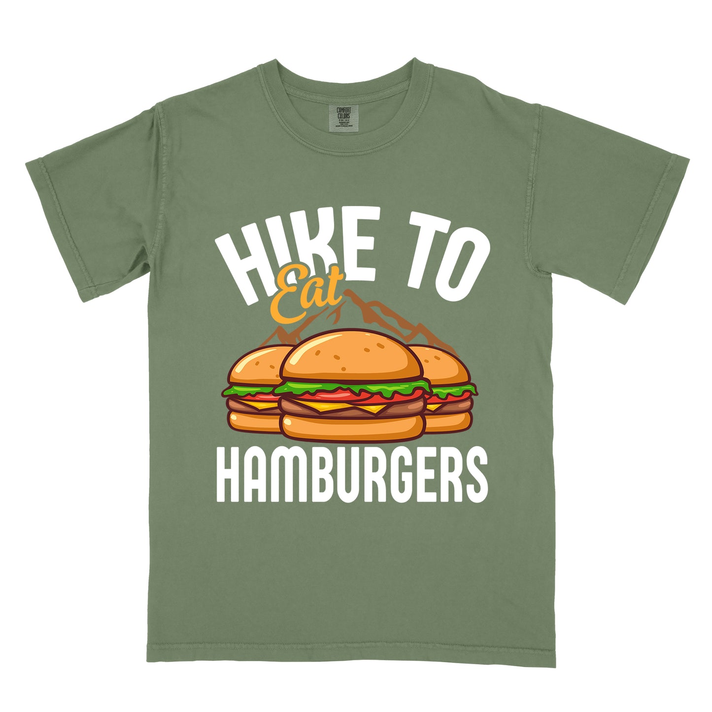 Moss (Dark Green) t-shirt with text "HIKE TO Eat HAMBURGERS". "HIKE TO" appears in white arched letters at the top, "Eat" in orange script in the middle, and "HAMBURGERS" in white at the bottom. The center features an illustration of three hamburgers with buns, lettuce, tomato, cheese and beef patties, with brown mountain silhouettes behind them. The design connects hiking activity with food rewards.