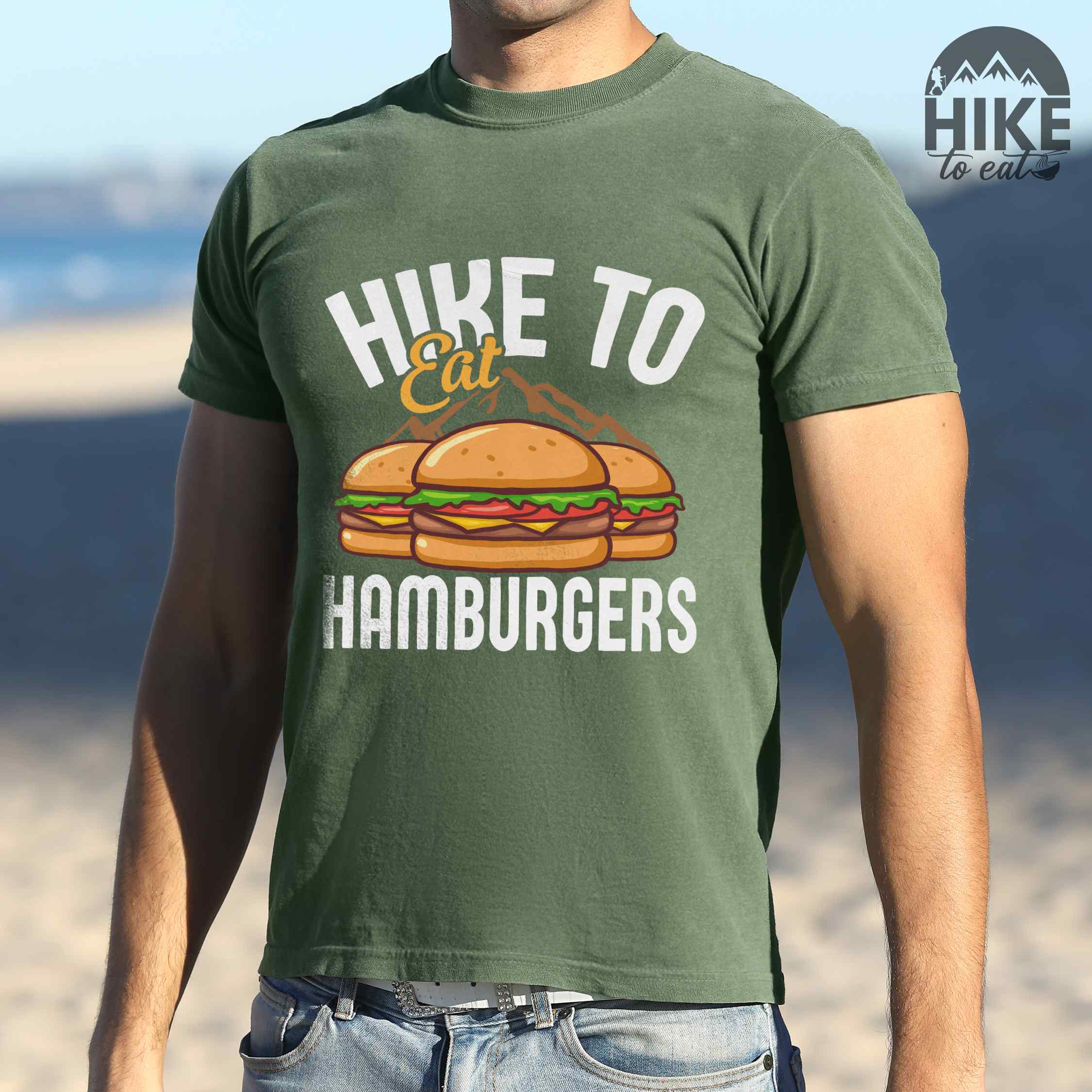 Man wearing moss "Hike to Eat Hamburgers" colored vintage tee with bold typography, illustrated juicy hamburger, and backpacker for burger enthusiasts.