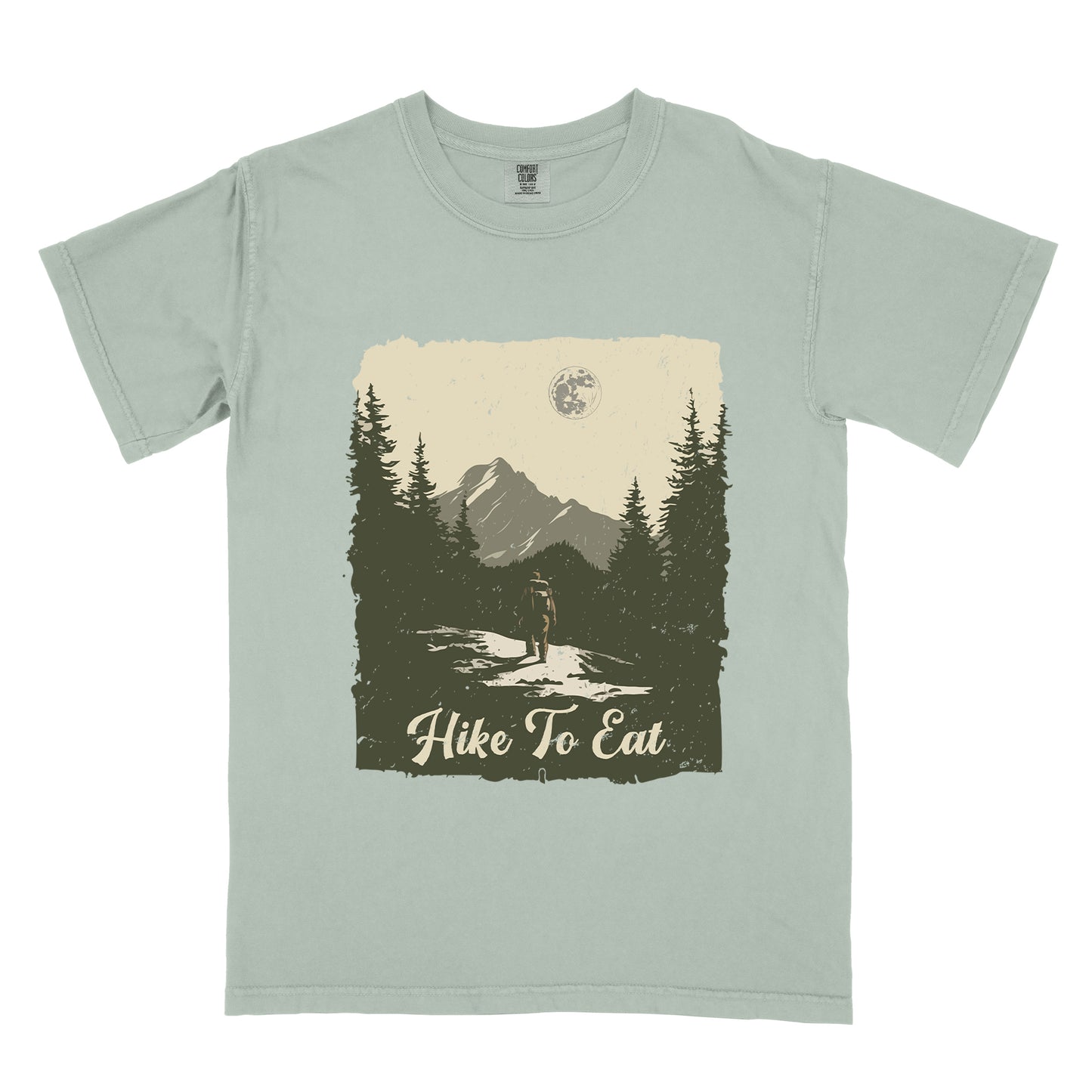Bay (Light Gray) t-shirt featuring a vintage-style illustration of a lone hiker on a mountain trail. The rectangular design shows pine trees, mountain silhouettes, and a full moon against a cream-colored sky. A solitary hiker with backpack stands on the path facing the mountains. "Hike To Eat" appears in cream script at the bottom of the illustration. The artwork uses muted green, cream, and gray tones in a distressed, rustic style.
