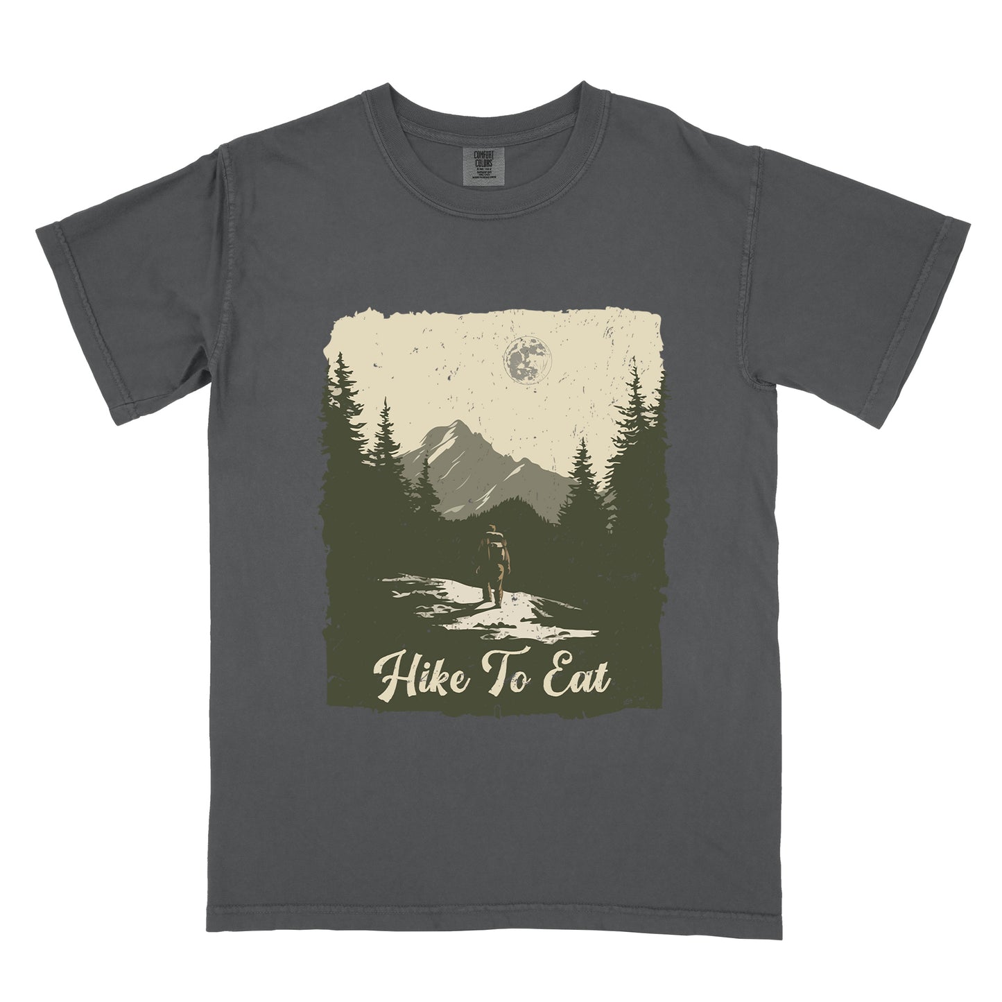Graphite (Deep Gray) t-shirt featuring a vintage-style illustration of a lone hiker on a mountain trail. The rectangular design shows pine trees, mountain silhouettes, and a full moon against a cream-colored sky. A solitary hiker with backpack stands on the path facing the mountains. "Hike To Eat" appears in cream script at the bottom of the illustration. The artwork uses muted green, cream, and gray tones in a distressed, rustic style.