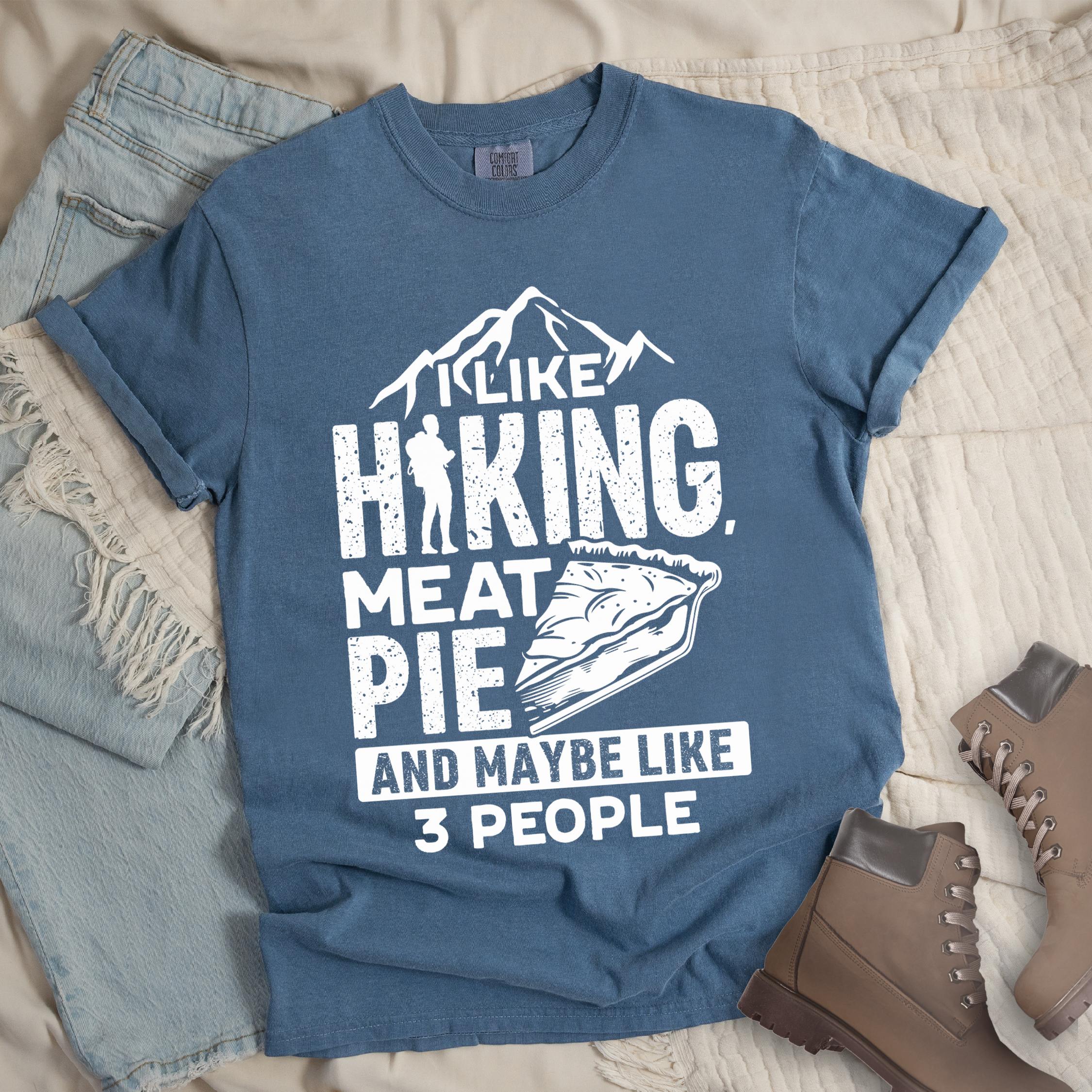 Dark blue shirt with Hiking Design featuring the phrase “I Like Hiking, Meat Pie, and Maybe Like 3 People” with a hiker silhouette, mountain outline, and an illustration of a meat pie slice.