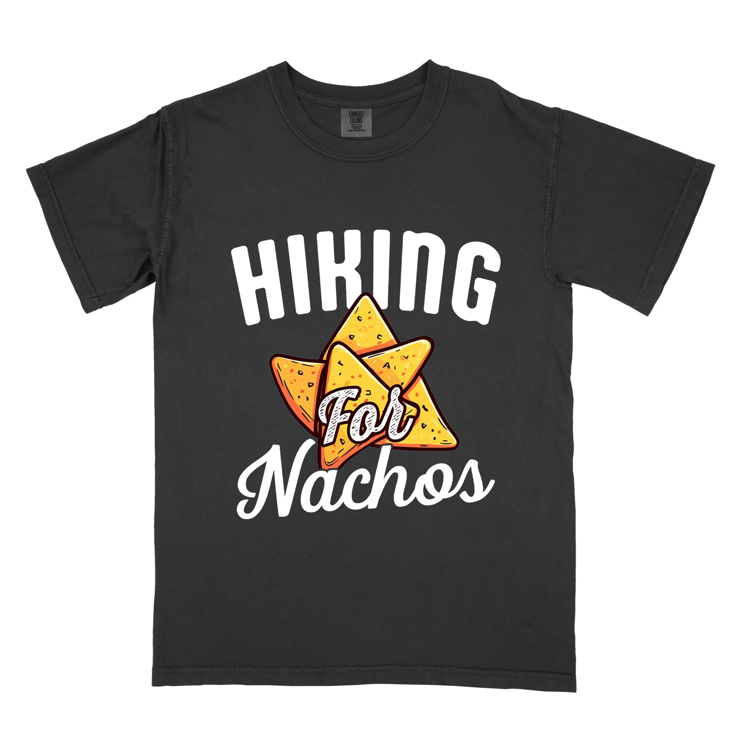 Black t-shirt with white text reading "HIKING For Nachos". "HIKING" appears in large white letters at the top, "For" in white script across the middle, and "Nachos" in white script at the bottom. The centerpiece of the design is an illustration of tortilla chips arranged in a star-like pattern, colored yellow-orange with flecks to represent seasonings. The design connects hiking activity with food motivation.