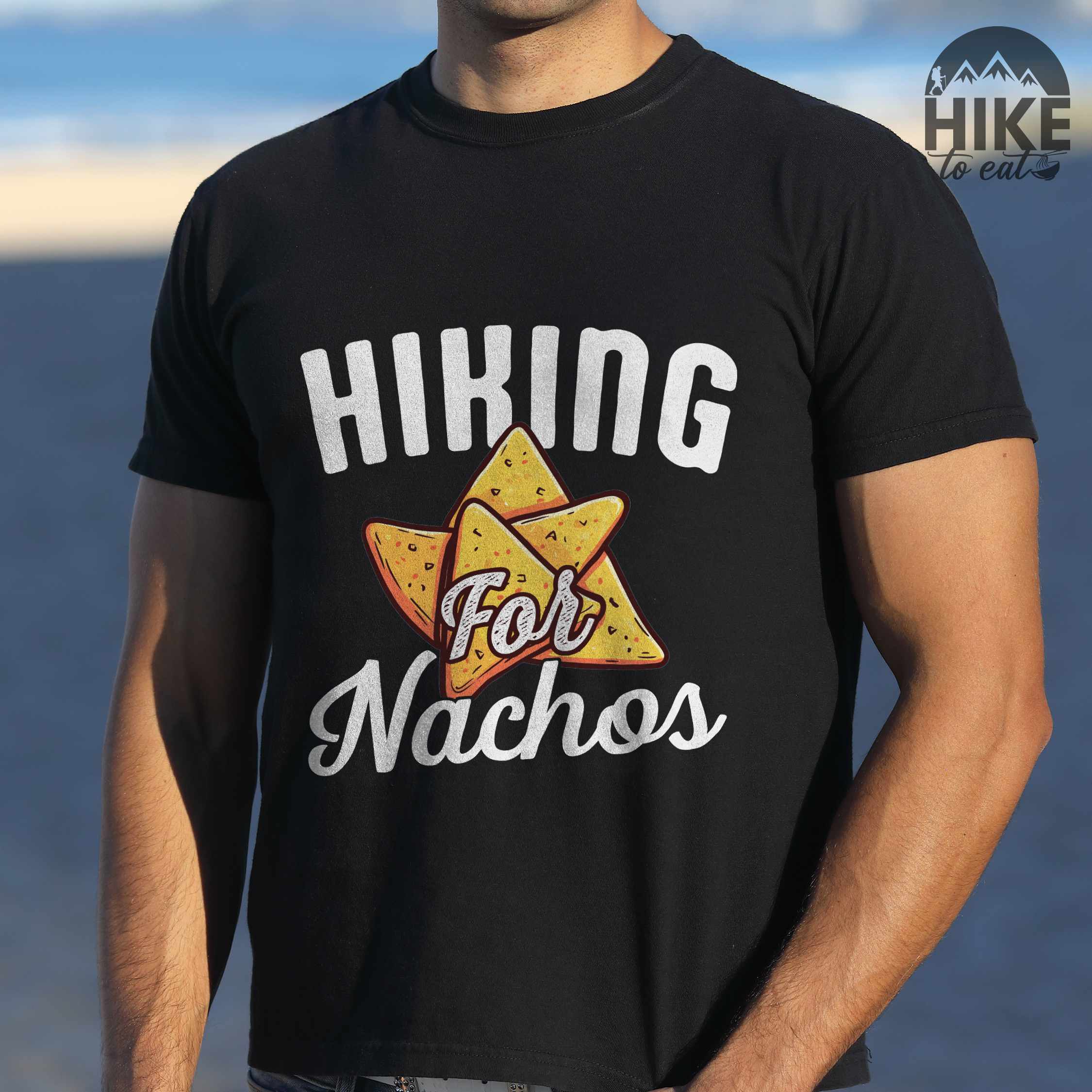 Man wearing black "Hiking for Nachos" colored vintage tee with bold typography, illustrated crispy nachos chips, and backpacker craving for chips.