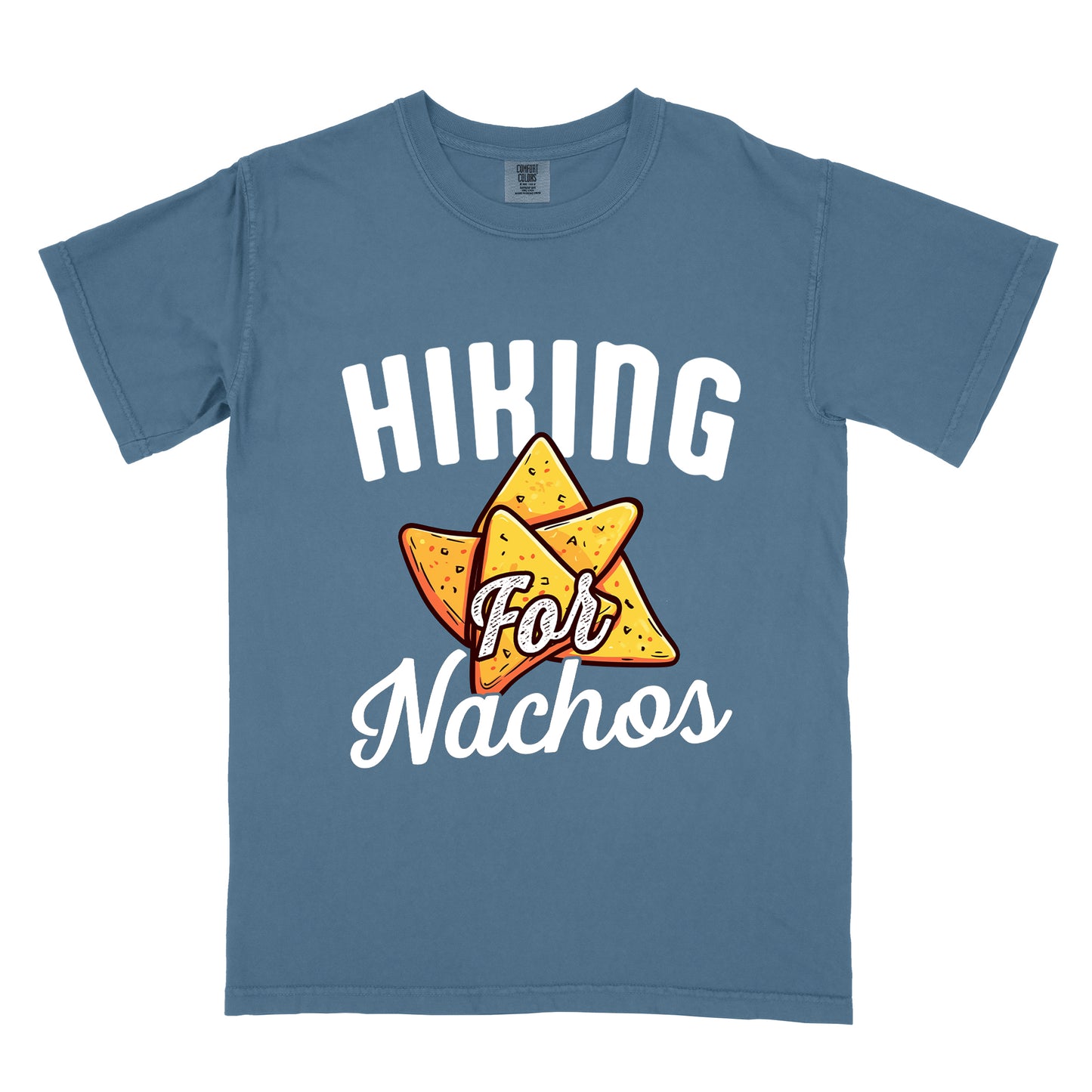 Blue Jean (Denim Blue) t-shirt with white text reading "HIKING For Nachos". "HIKING" appears in large white letters at the top, "For" in white script across the middle, and "Nachos" in white script at the bottom. The centerpiece of the design is an illustration of tortilla chips arranged in a star-like pattern, colored yellow-orange with flecks to represent seasonings. The design connects hiking activity with food motivation.