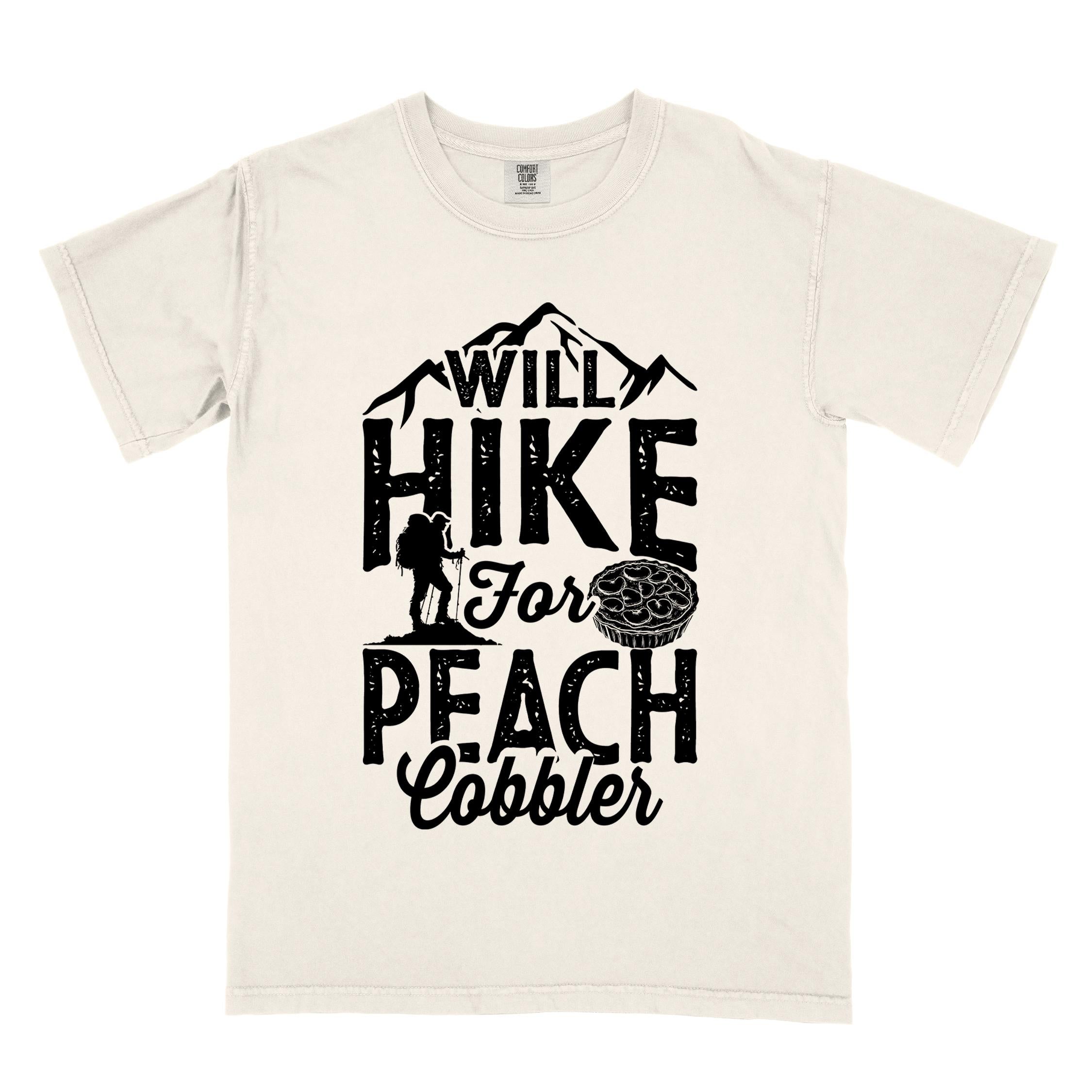 Ivory "Will hike for peach cobbler" colored vintage tee with bold typography, mountain, birds, illustrated peach cobbler, and backpacker looking for sweet treats.