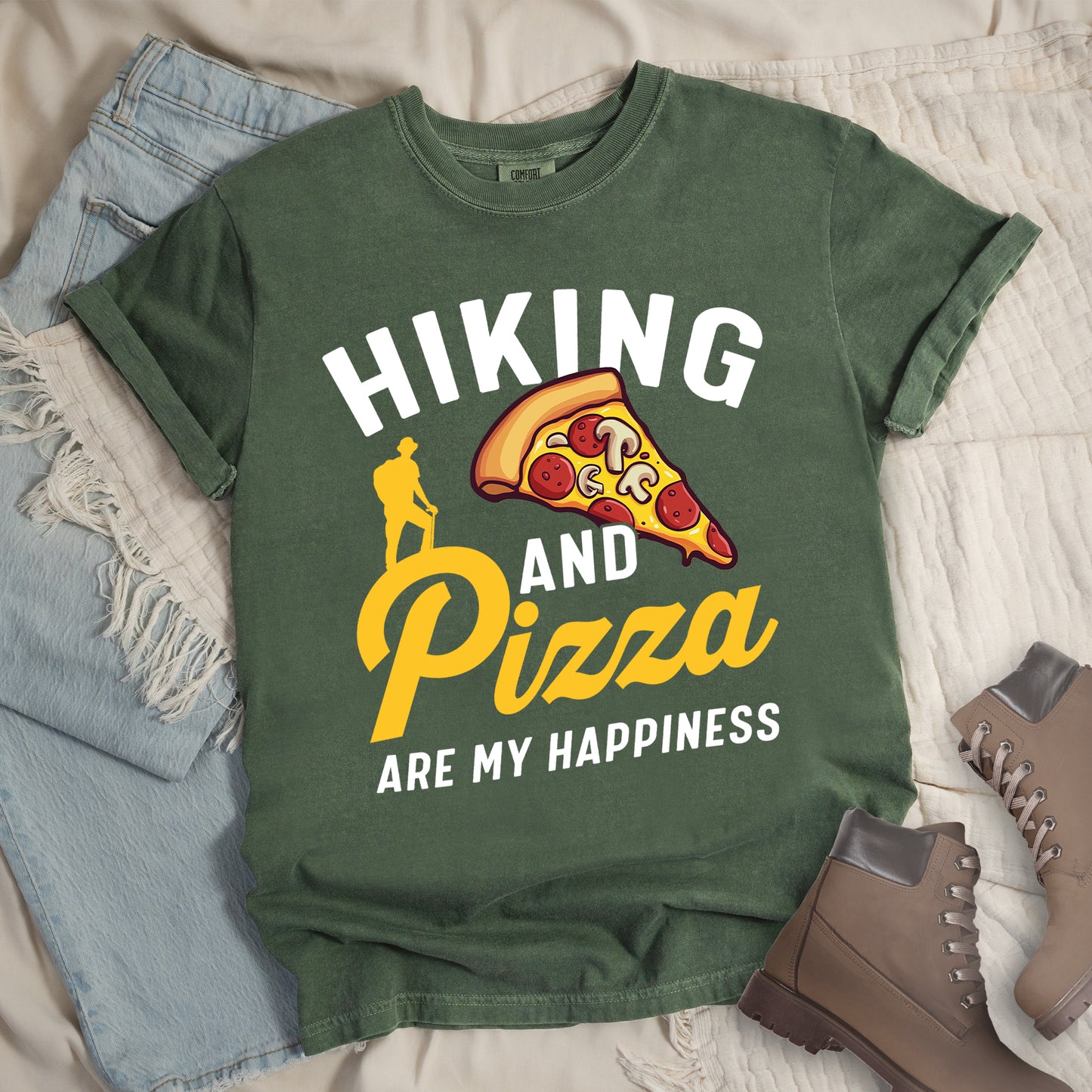 Moss (Dark Green) t-shirt with white and yellow text reading "HIKING AND Pizza ARE MY HAPPINESS". "HIKING" appears in white at the top, "AND" in white in the middle, "Pizza" in yellow script, and "ARE MY HAPPINESS" in white at the bottom. Features a colorful pizza slice with pepperoni and mushrooms in the center-right and a yellow silhouette of a hiker on the left side above "AND Pizza ARE MY HAPPINESS". The design combines outdoor activity with food enjoyment.