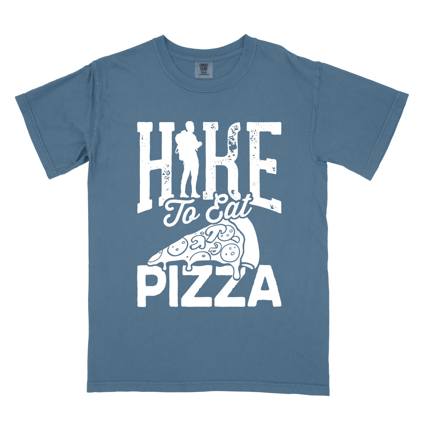 Blue Jean (Denim Blue) t-shirt with white distressed text reading "HIKE To Eat PIZZA". "HIKE" appears in large block letters at the top with a silhouette of a hiker with backpack integrated into the "I", "To Eat" in script in the middle, and "PIZZA" in large block letters at the bottom. Features a simple line drawing of a pizza slice with toppings between the phrases. The design humorously connects hiking activity with pizza as a reward.
