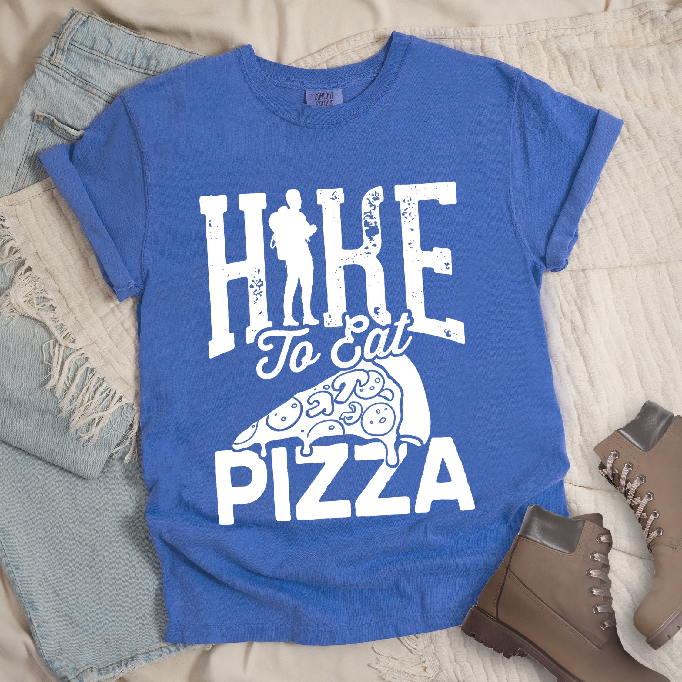 Blue shirt with Hiking Design featuring the phrase “Hike to Eat Pizza” with a bold hiker silhouette and an illustration of a large pizza slice.