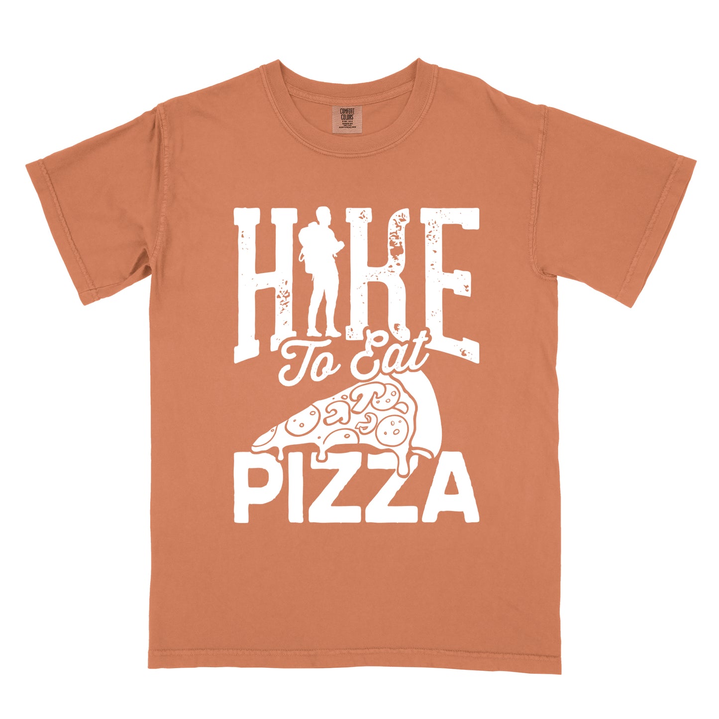 Yam (Brown) t-shirt with white distressed text reading "HIKE To Eat PIZZA". "HIKE" appears in large block letters at the top with a silhouette of a hiker with backpack integrated into the "I", "To Eat" in script in the middle, and "PIZZA" in large block letters at the bottom. Features a simple line drawing of a pizza slice with toppings between the phrases. The design humorously connects hiking activity with pizza as a reward.