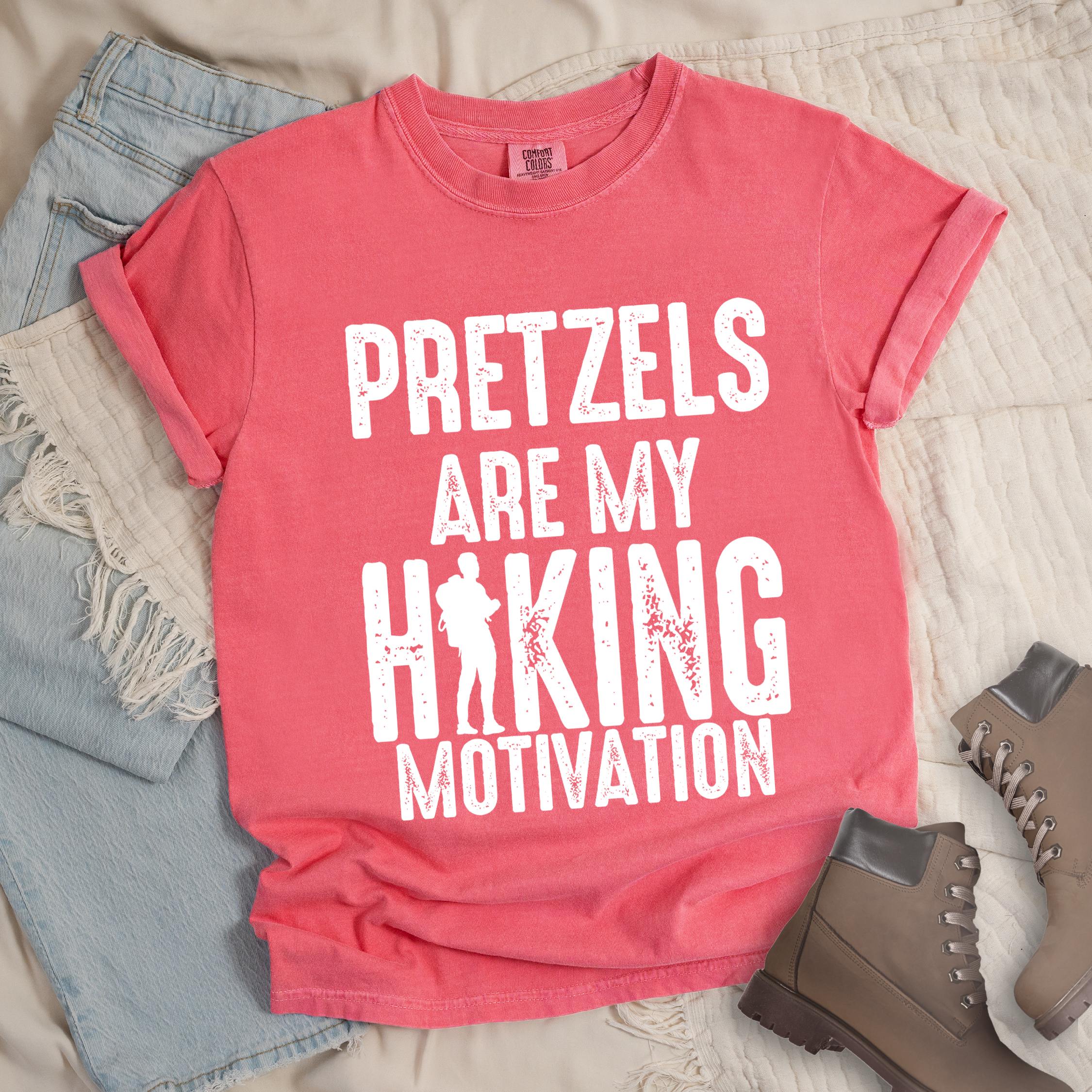 Pink shirt with Hiking Design featuring the phrase “Pretzels Are My Hiking Motivation” and a silhouette of a hiker replacing the letter “I” in the word “Hiking.”