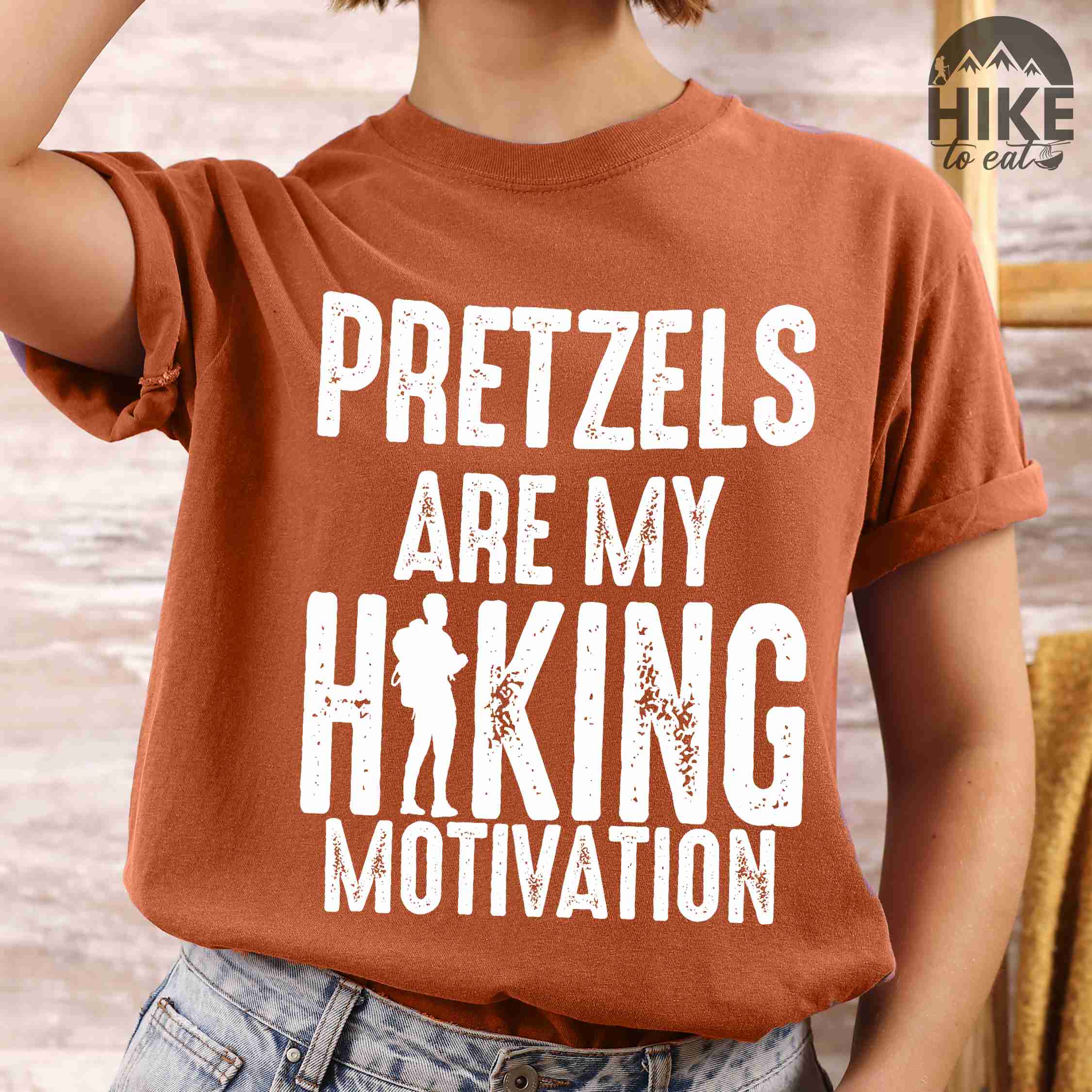 woman wearing yam "Pretzels are my hiking motivation" colored vintage tee with bold typography, and backpacker for pretzel lovers.