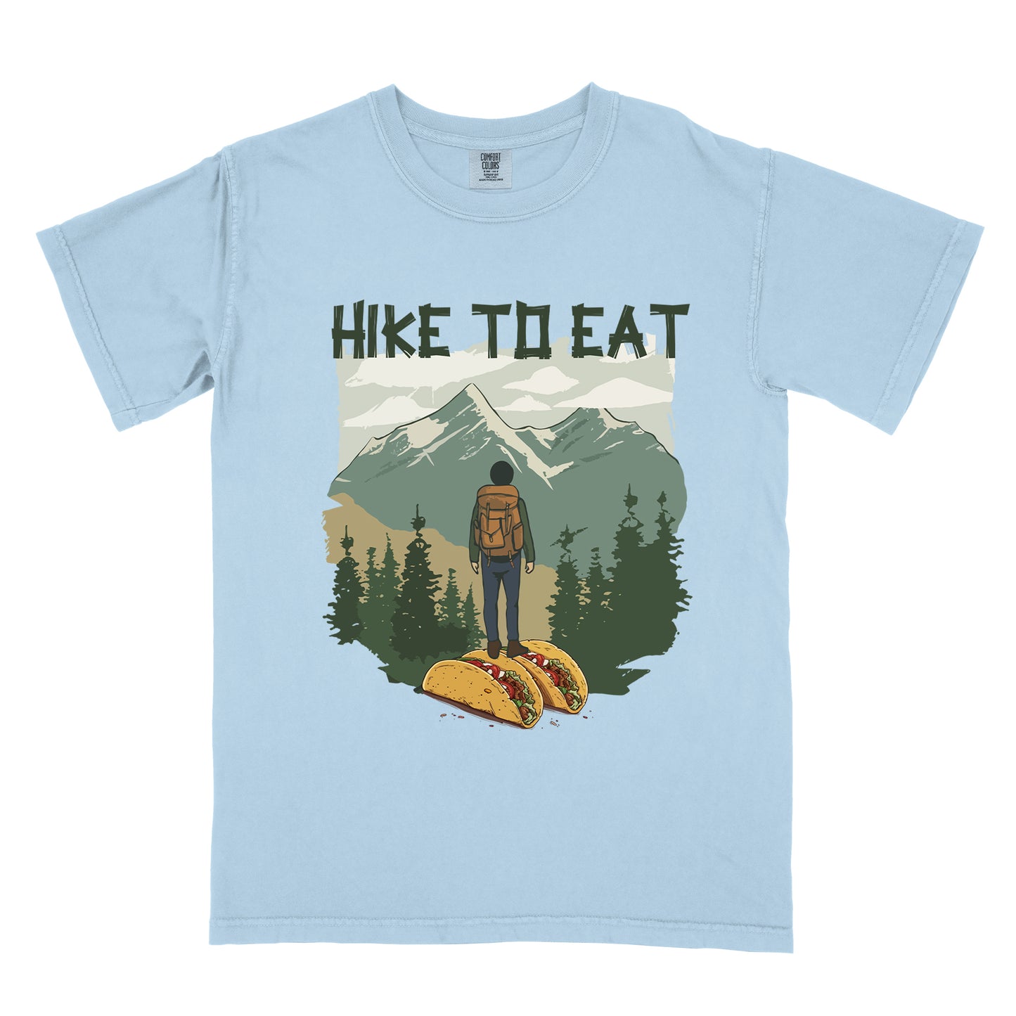 Light Blue (Chambray) t-shirt with "HIKE TO EAT" printed at the top in dark green text. The main graphic shows a hiker with backpack standing on two tacos, facing a scenic mountain landscape with pine trees in the foreground and snow-capped peaks in the background.