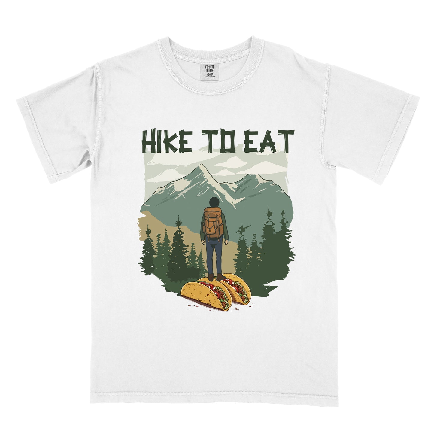 White t-shirt with "HIKE TO EAT" printed at the top in dark green text. The main graphic shows a hiker with backpack standing on two tacos, facing a scenic mountain landscape with pine trees in the foreground and snow-capped peaks in the background.