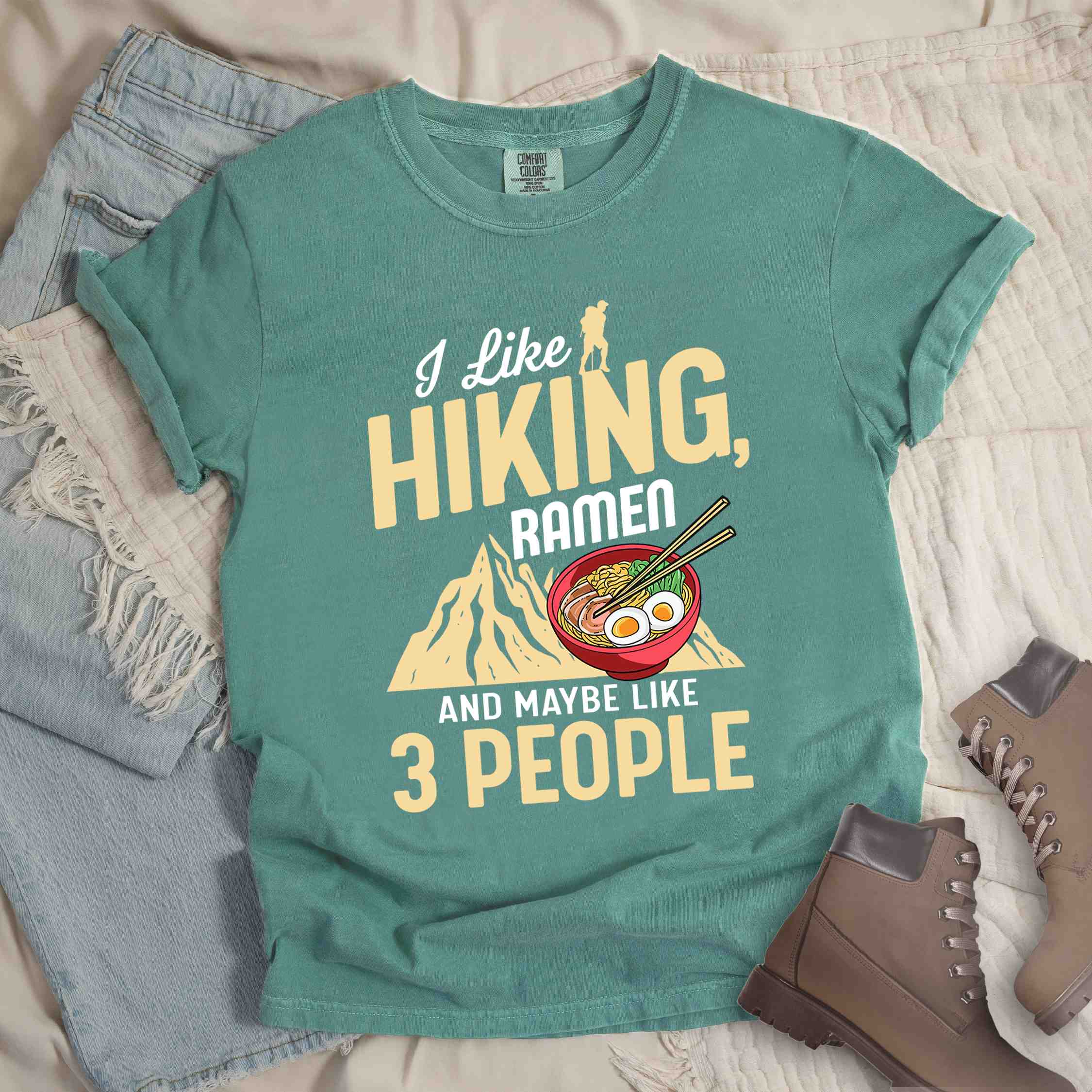 Light green “Ramen is my Hiking motivation” colored vintage tee with bold text, mountain, Illustration of hot ramen. Perfect tee for a foodie craving for a bowl of ramen,