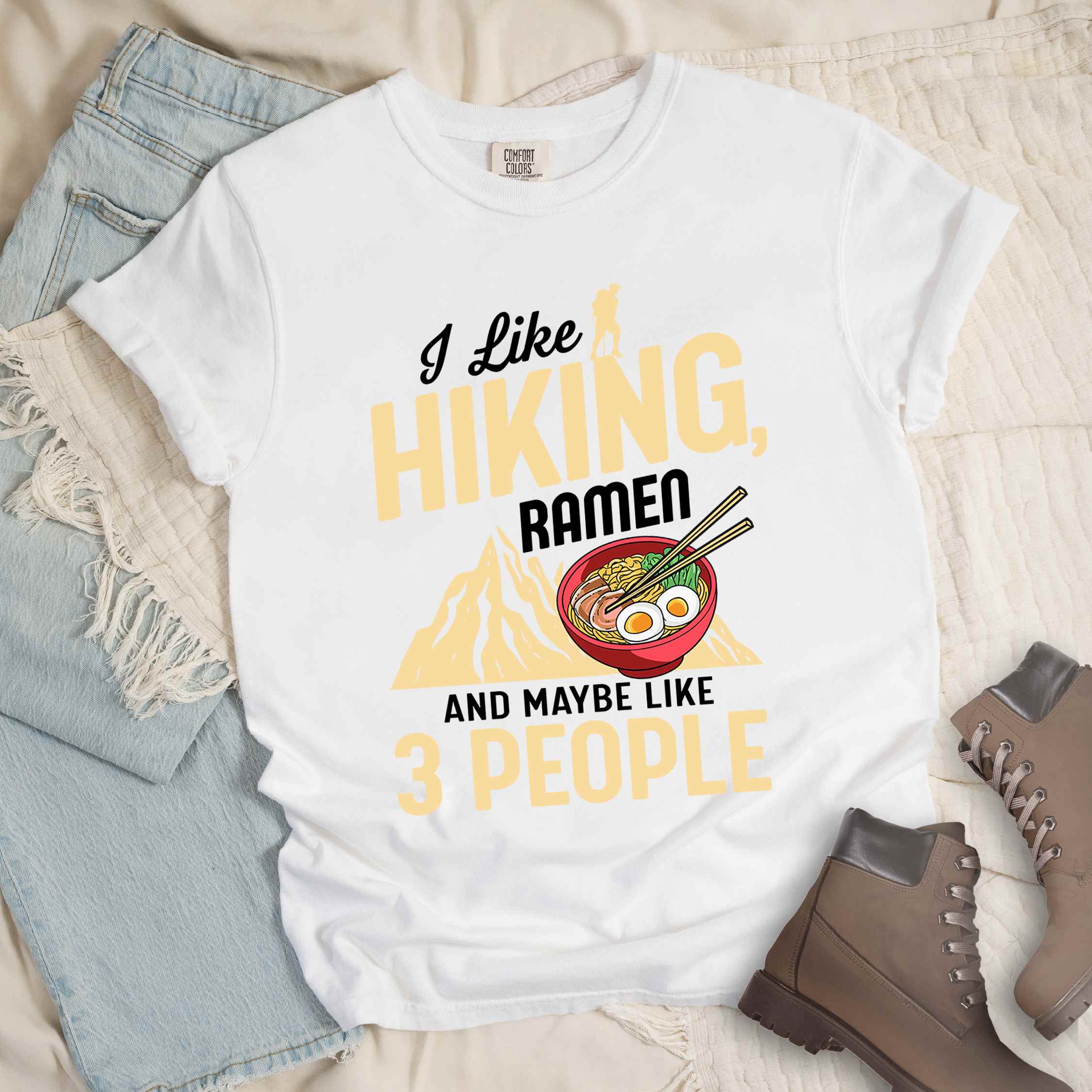 White “Ramen is my Hiking motivation” colored vintage tee with bold text, mountain, Illustration of hot ramen. Perfect tee for a foodie craving for a bowl of ramen,