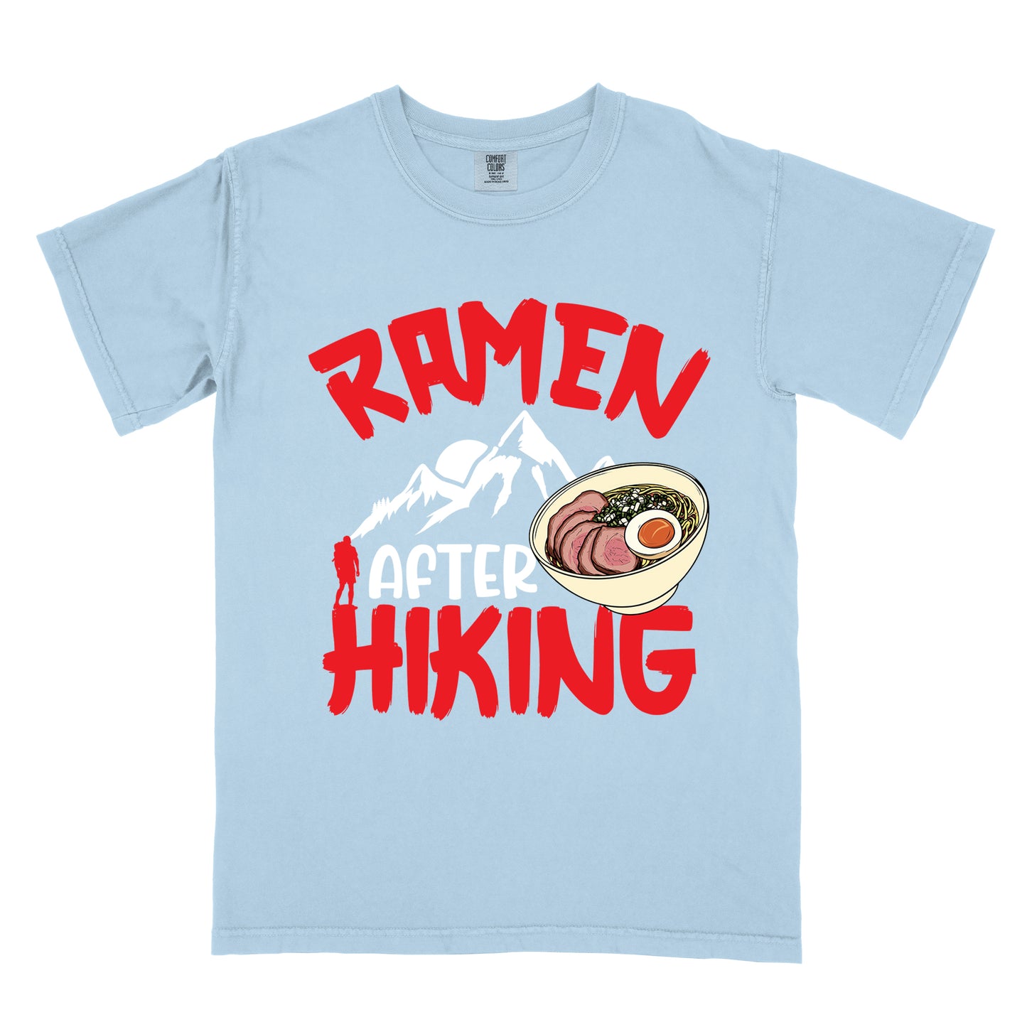 Chambray (Light Blue) t-shirt with red text reading "RAMEN AFTER HIKING". "RAMEN" appears in bold red letters at the top, "AFTER" in white in the middle, and "HIKING" in bold red at the bottom. Features white mountain silhouettes in the center with a red hiker figure, and a detailed illustration of a ramen bowl with sliced meat, egg, and green onions on the right. The design connects outdoor activities with food rewards.