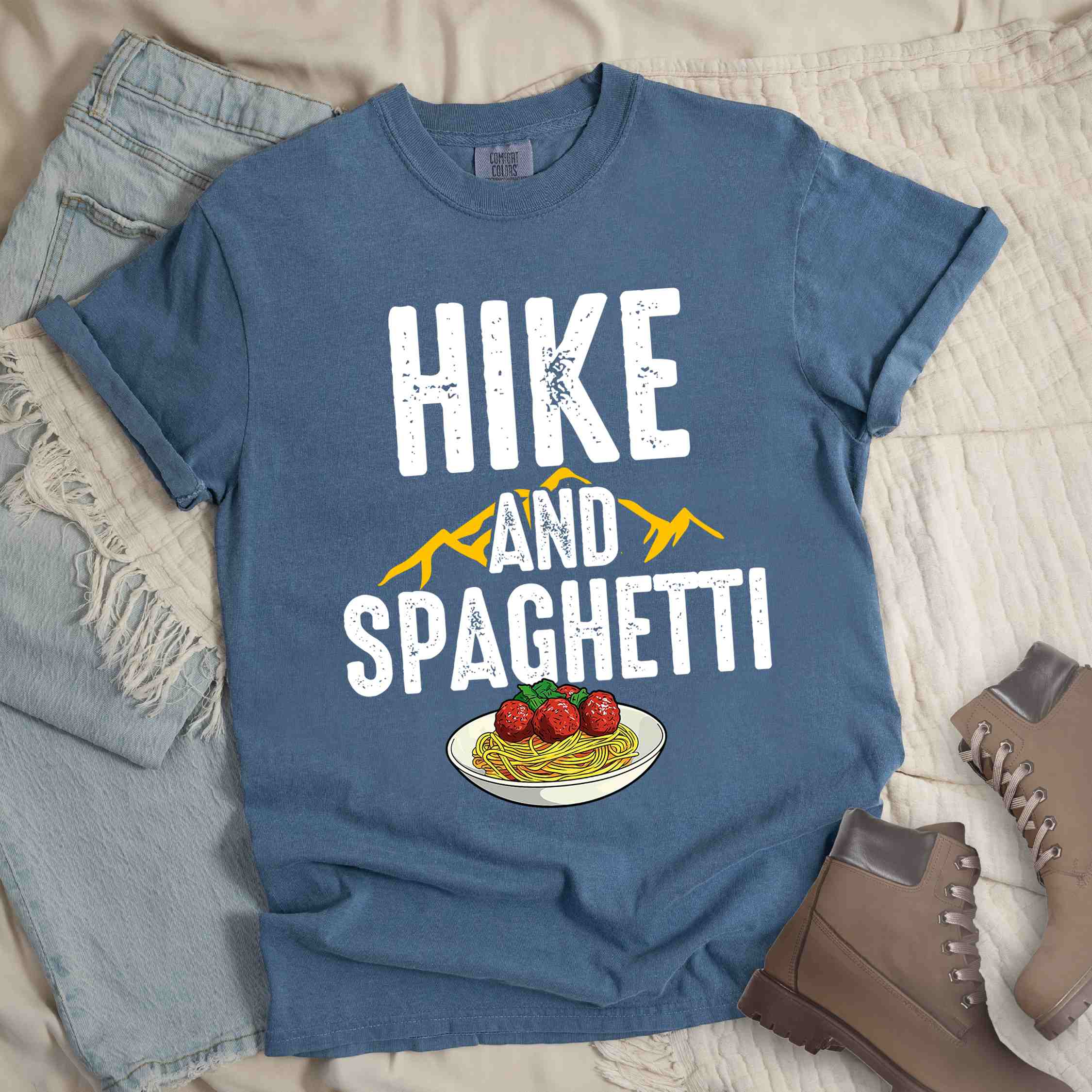 Blue jean "Hike and Spaghetti" colored vintage tee with bold typography, birds, mountains, illustrated plate of spaghetti and meatballs, and backpacker for pasta lovers.