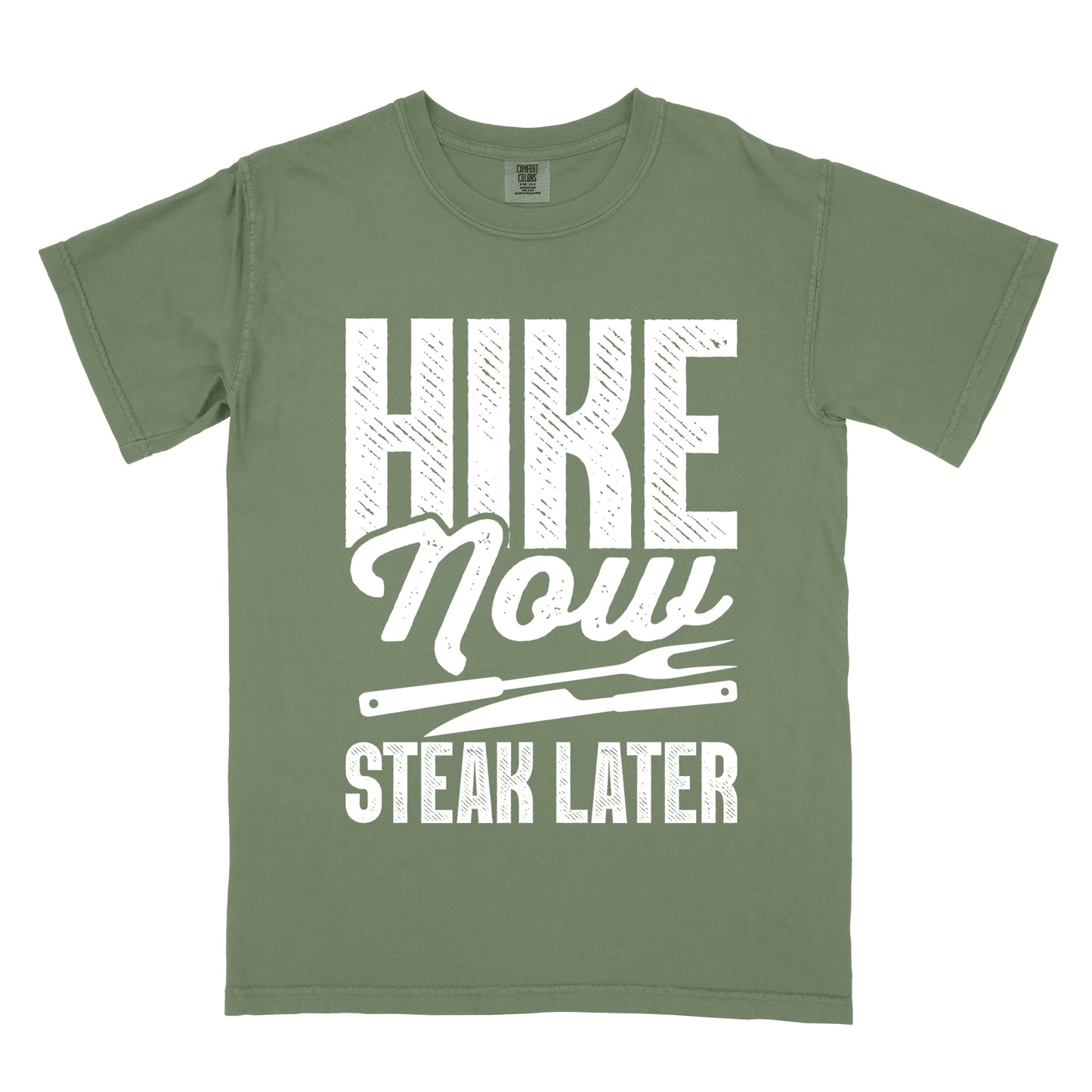 Moss (Dark Green) t-shirt with white distressed text reading "HIKE Now STEAK LATER". "HIKE" appears in large bold block letters at the top, "Now" in stylish script in the middle, and "STEAK LATER" in block letters at the bottom. Between the middle and bottom text is a simple illustration of a steak knife. The design emphasizes the reward of enjoying steak after completing a hiking activity.