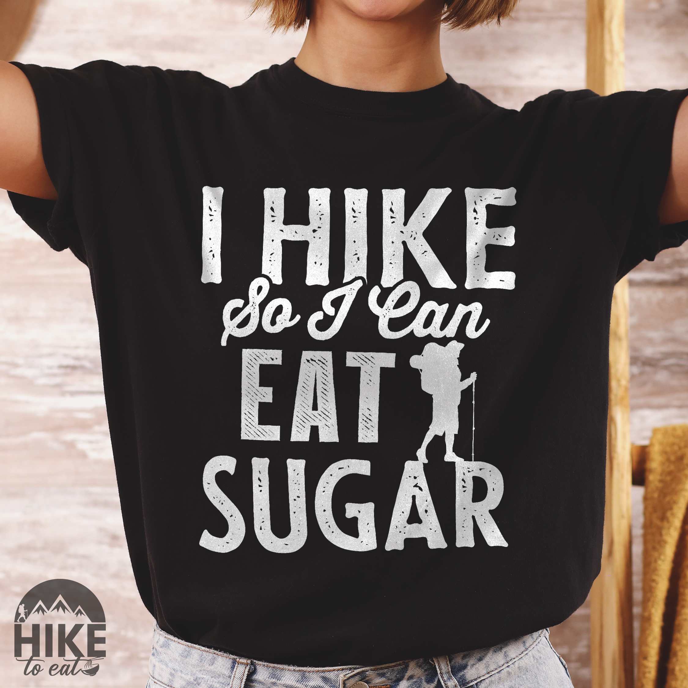Woman wearing black "I hike so I can eat sugar" colored vintage tee with bold typography, and backpacker with a sweet tooth.