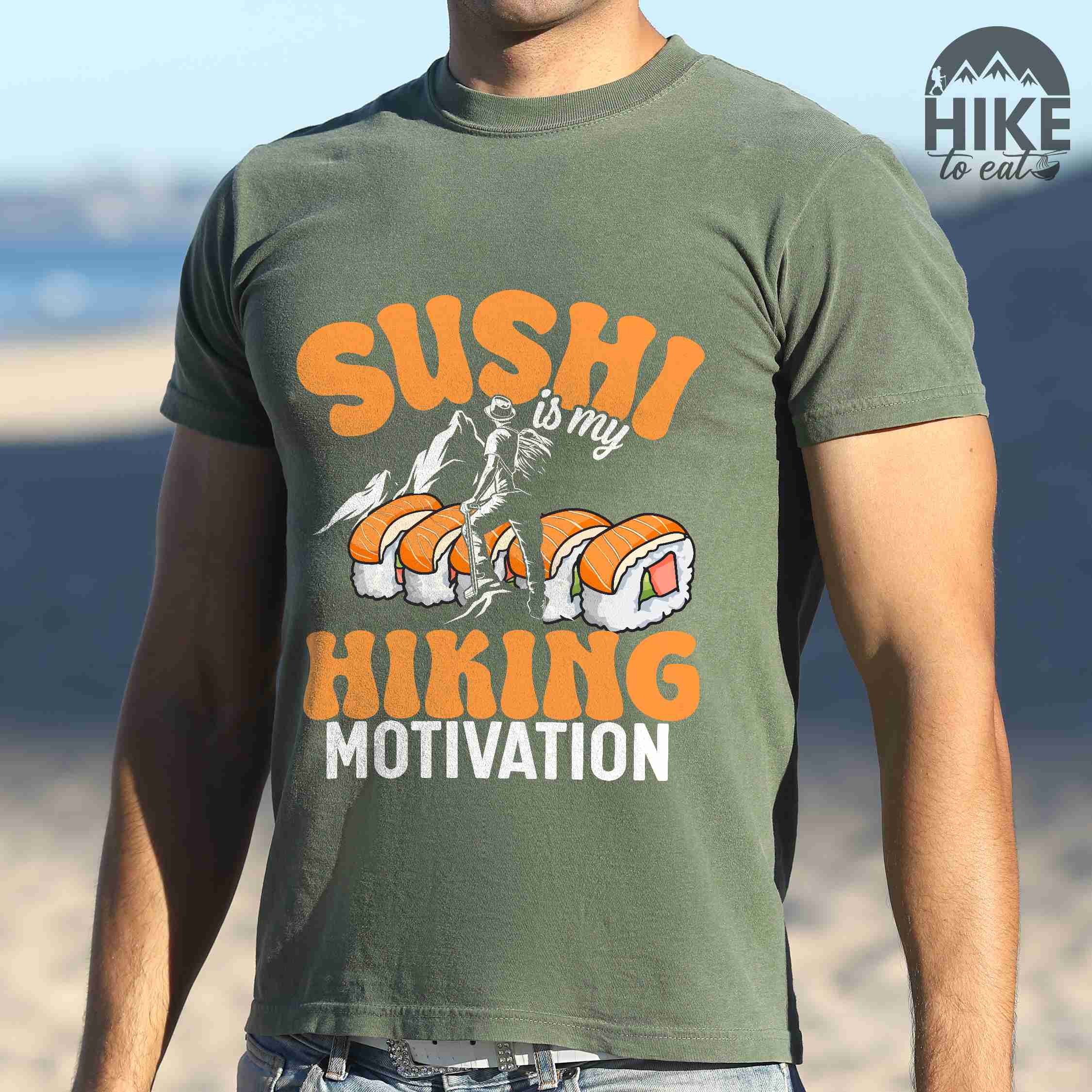Man wearing moss "sushi is my hiking motivation" colored vintage tee with bold typography, birds, mountains, illustrated sushi platter, and backpacker for sushi lovers.