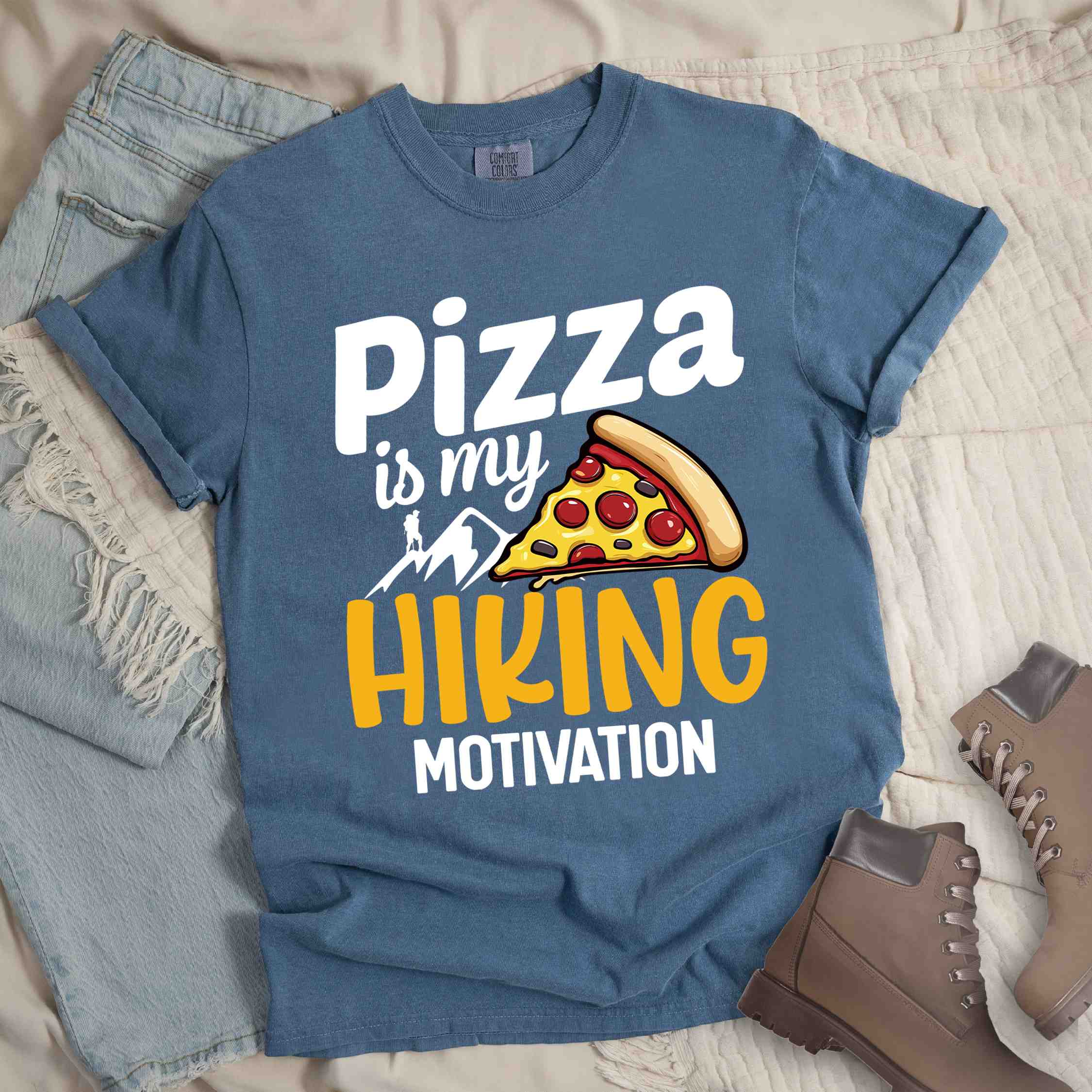Blue jean "Pizza is my hiking motivation" colored vintage tee with bold typography, birds, mountains, illustrated pizza slice, and backpacker for pizza lovers.