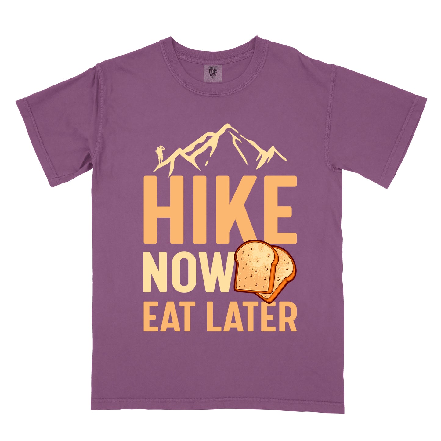 A Berry (Dark Violet) t-shirt with a design showing "HIKE NOW EAT LATER" in gradient orange and tan text. Above "HIKE" is a mountain silhouette with a small hiker figure. A sandwich/toast illustration appears between "NOW" and "EAT LATER". The text is arranged in three lines with "HIKE" at the top in largest font, followed by "NOW" and "EAT LATER" below.