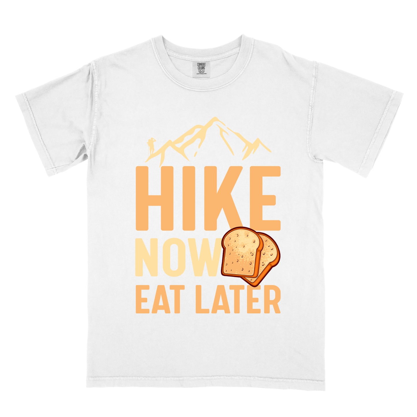 A white t-shirt with a design showing "HIKE NOW EAT LATER" in gradient orange and tan text. Above "HIKE" is a mountain silhouette with a small hiker figure. A sandwich/toast illustration appears between "NOW" and "EAT LATER". The text is arranged in three lines with "HIKE" at the top in largest font, followed by "NOW" and "EAT LATER" below.