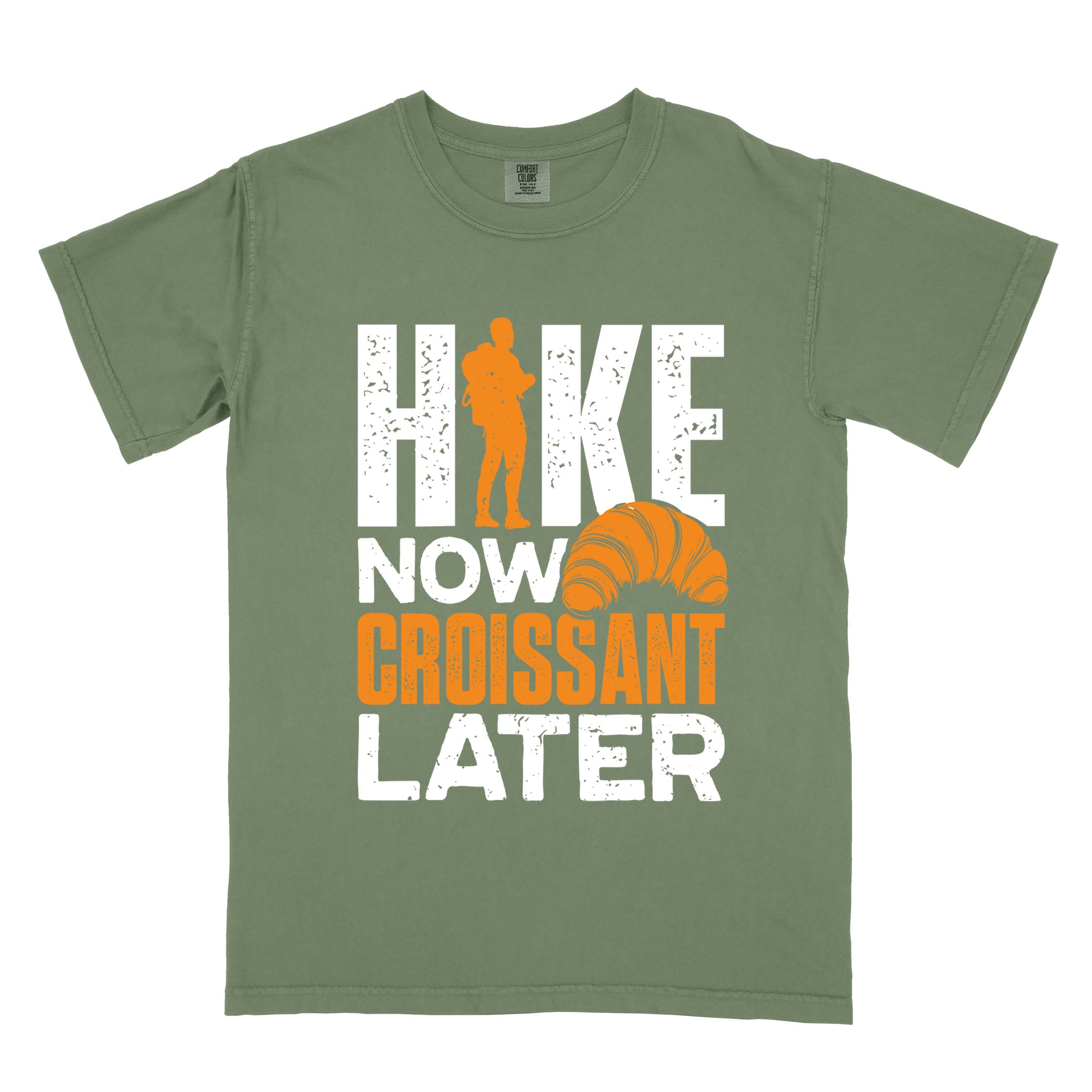 Moss "Hike now croissant later" colored vintage tee with bold typography, birds, mountains, illustrated baked croissant, and backpacker for pastry enthusiasts.