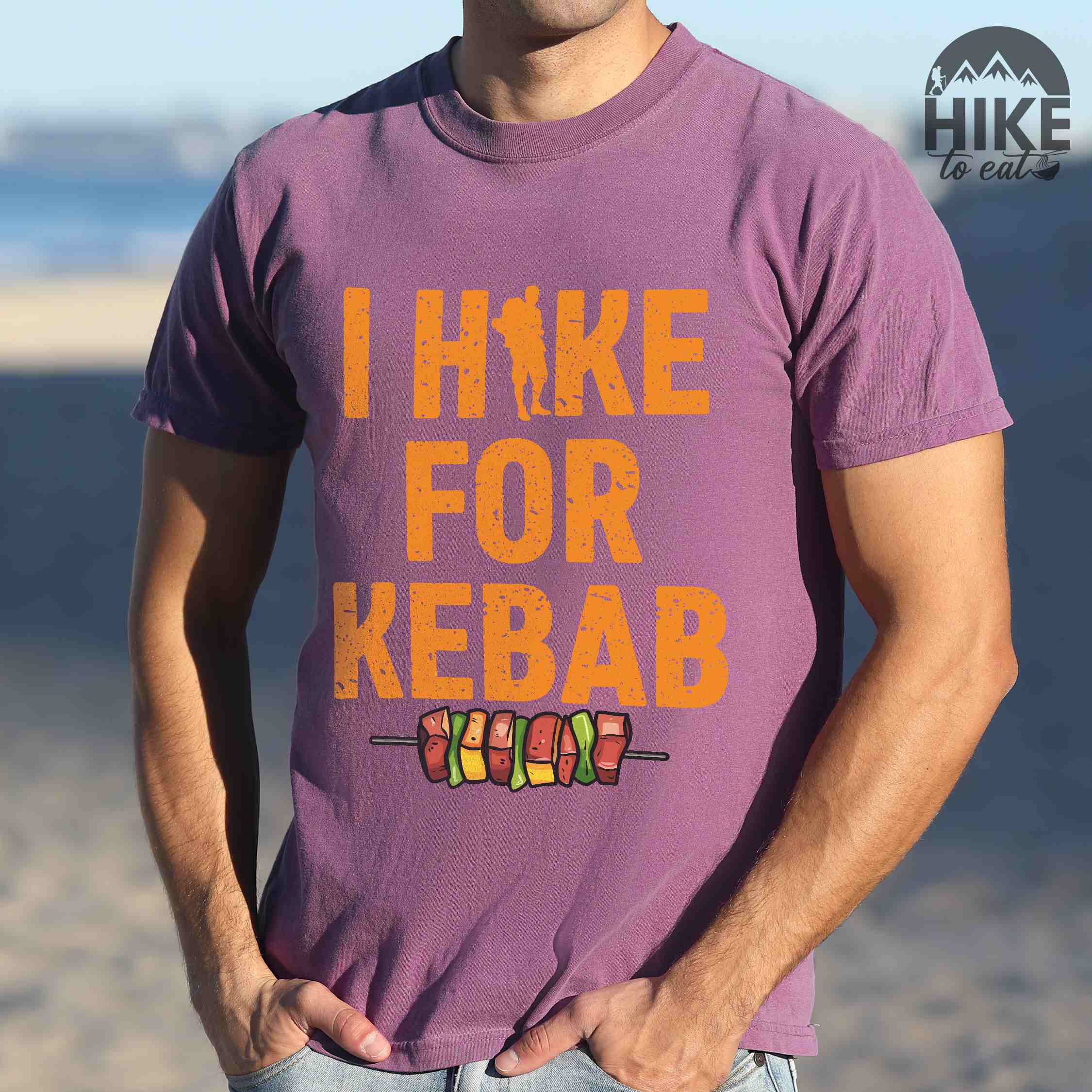 Man wearing berry "I hike for kebab" colored vintage tee with bold typography illustrated grilled kebabt, and backpacker for kebab lovers.
