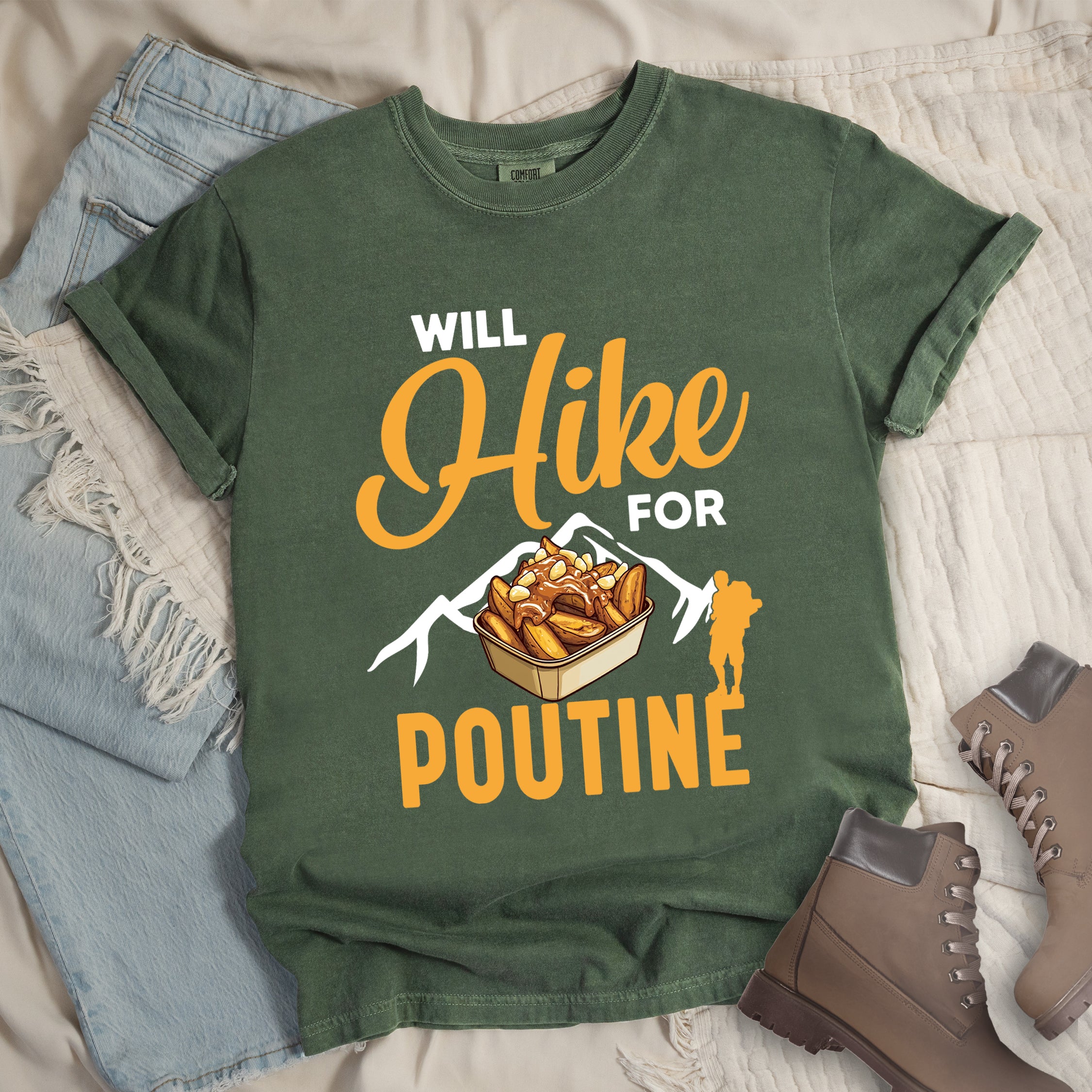 Moss (Dark Green) t-shirt with orange and white text reading "WILL Hike FOR POUTINE". "WILL" appears in white at the top, "Hike" in large orange script in the middle, "FOR" in white, and "POUTINE" in large orange letters at the bottom. Features a detailed illustration of a container of poutine (french fries with cheese curds and gravy) in the center, white mountain silhouettes behind it, and an orange hiker silhouette on the right.