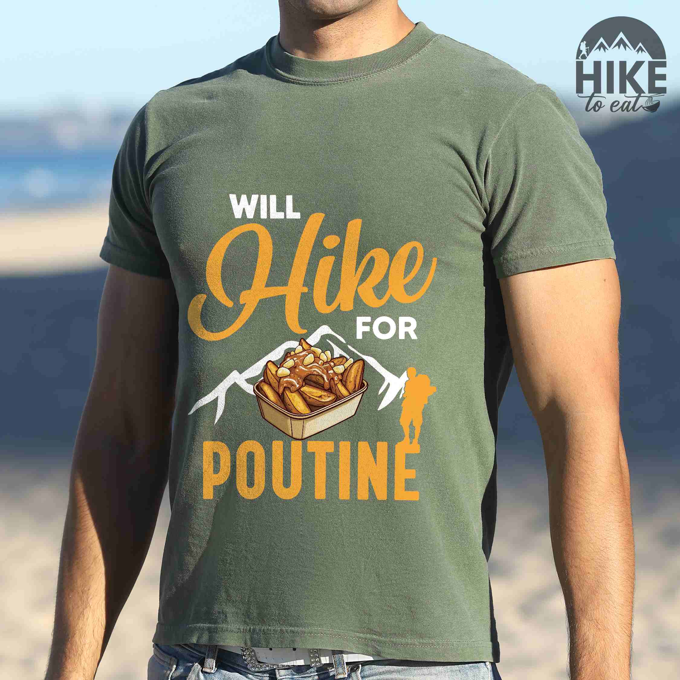 Man wearing moss "Will hike for poutine" colored vintage tee with bold typography, mountains, illustrated a serving of poutine and backpackers looking for comfort food.