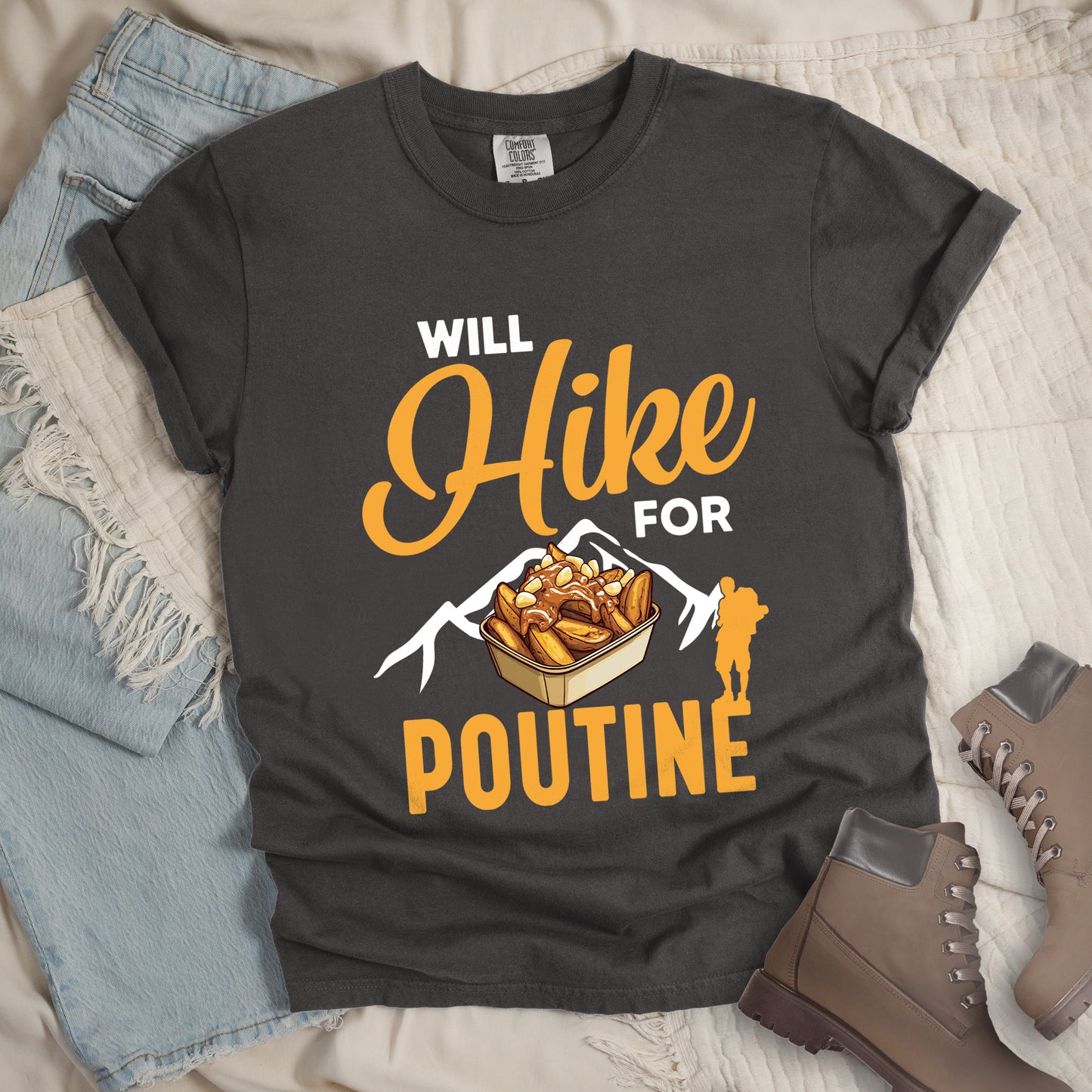 Pepper (Dark Gray) t-shirt with orange and white text reading "WILL Hike FOR POUTINE". "WILL" appears in white at the top, "Hike" in large orange script in the middle, "FOR" in white, and "POUTINE" in large orange letters at the bottom. Features a detailed illustration of a container of poutine (french fries with cheese curds and gravy) in the center, white mountain silhouettes behind it, and an orange hiker silhouette on the right.