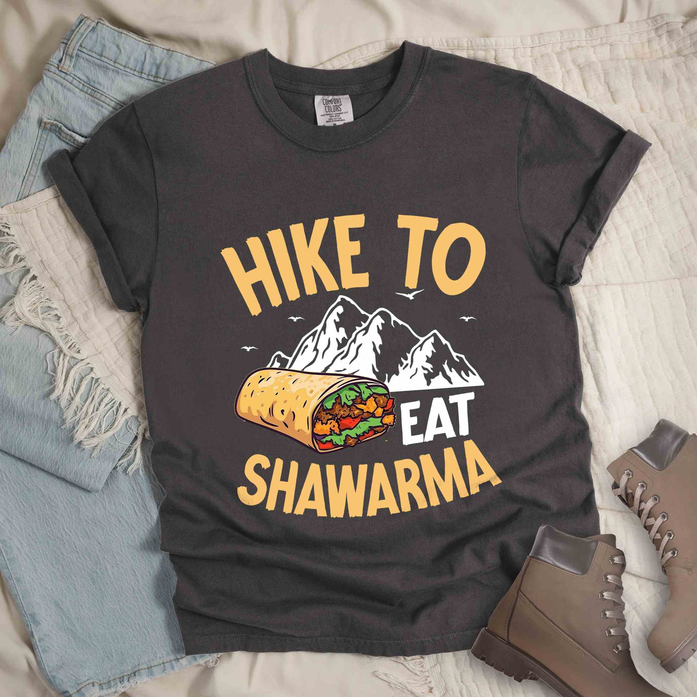 Pepper "Hike to Eat Shawarma" colored vintage tee with bold typography, mountains, birds, and illustrated shawarma, and backpackers for shawarma lovers.