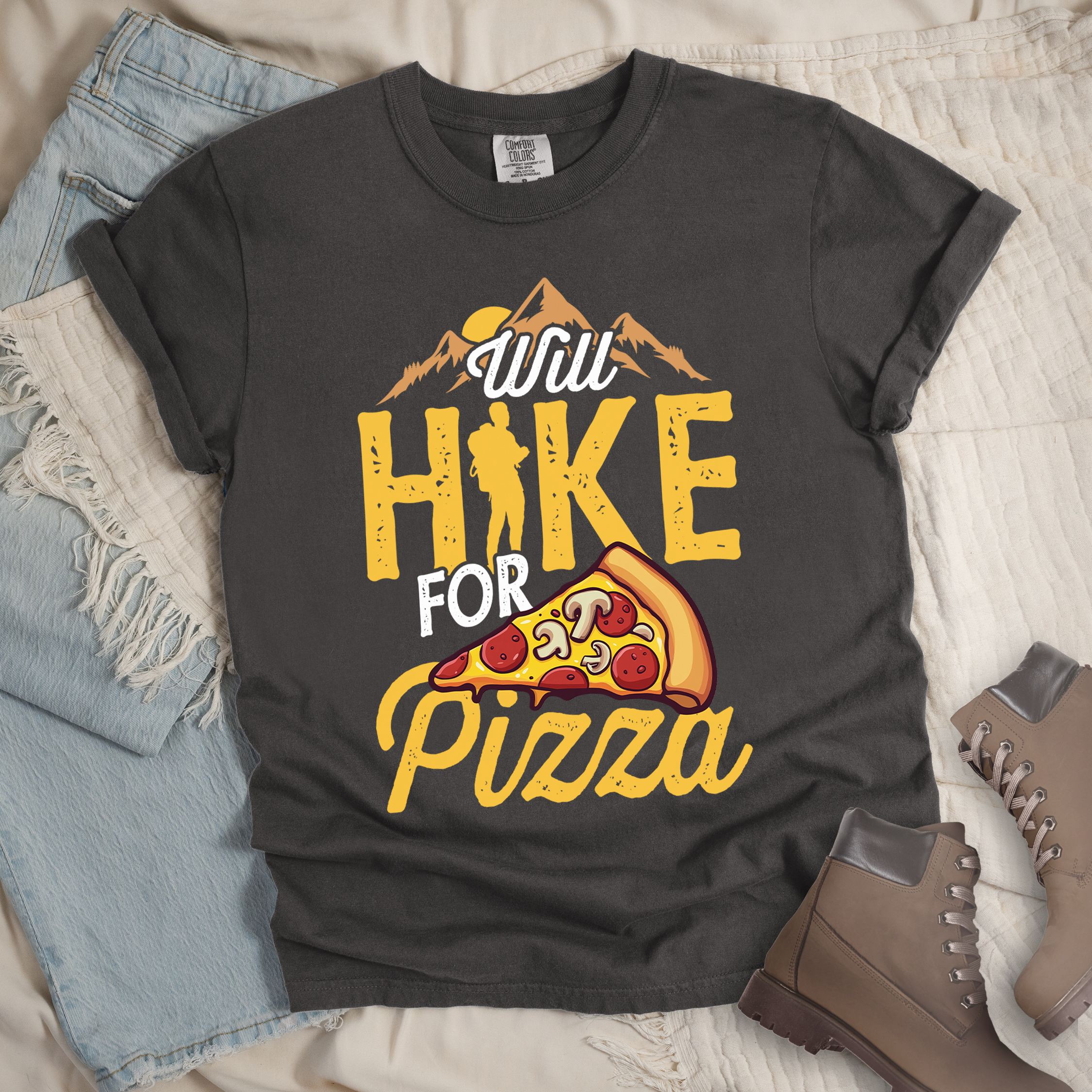 Dark grey shirt featuring Hiking design of mountains with a sunrise behind and a slice of pizza in front of the phrase 'Will Hike for Pizza'.