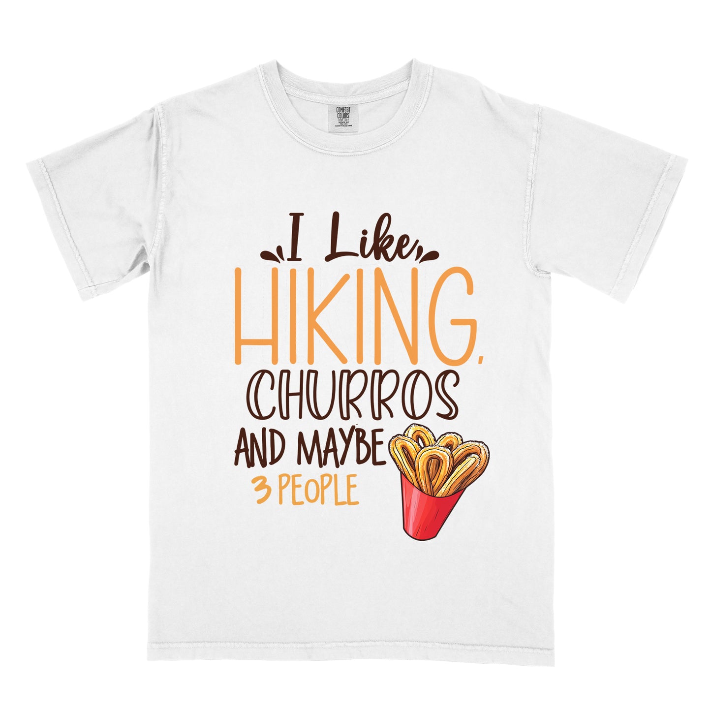 White t-shirt with deep brown and orange text reading "I Like HIKING, CHURROS AND MAYBE 3 PEOPLE". "I Like" appears in deep brown script at the top, "HIKING," in large orange letters, "CHURROS" in deep brown outlined letters, "AND MAYBE" in deep brown, and "3 PEOPLE" in small orange text at the bottom. Features an illustration of churros in a red container on the right side.