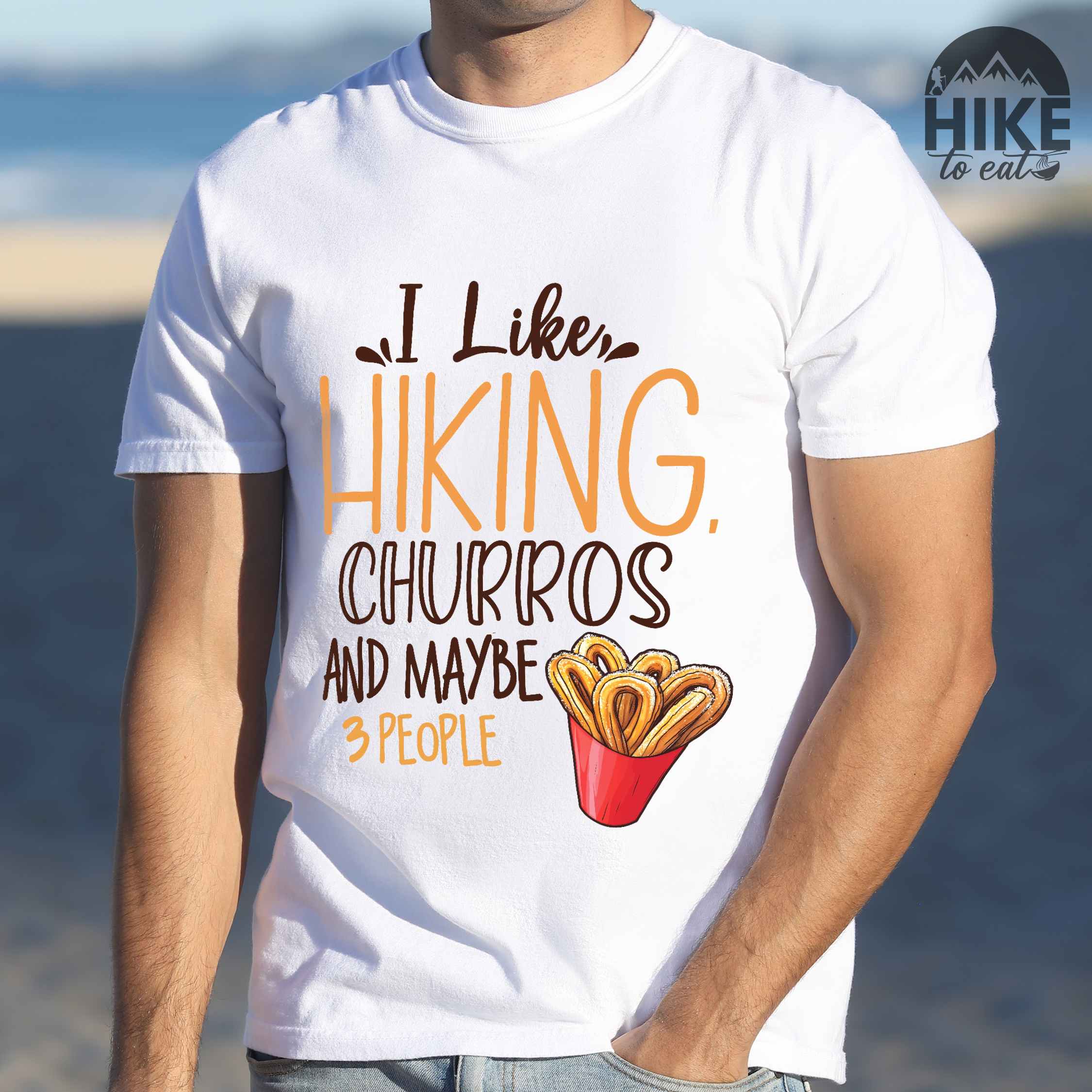 Man wearing white "I like hiking, churros and maybe three people " colored vintage tee with bold typography, mountains, illustrated a serving of Churros, and backpackers with a sweet tooth.