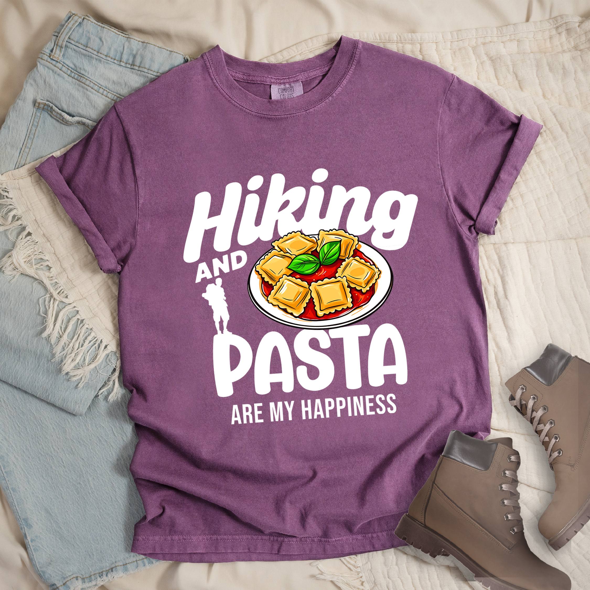 Dark pink shirt with the phrase “Hiking And Pasta Are My Happiness.” Shows a hiker silhouette and a ravioli plate illustration.