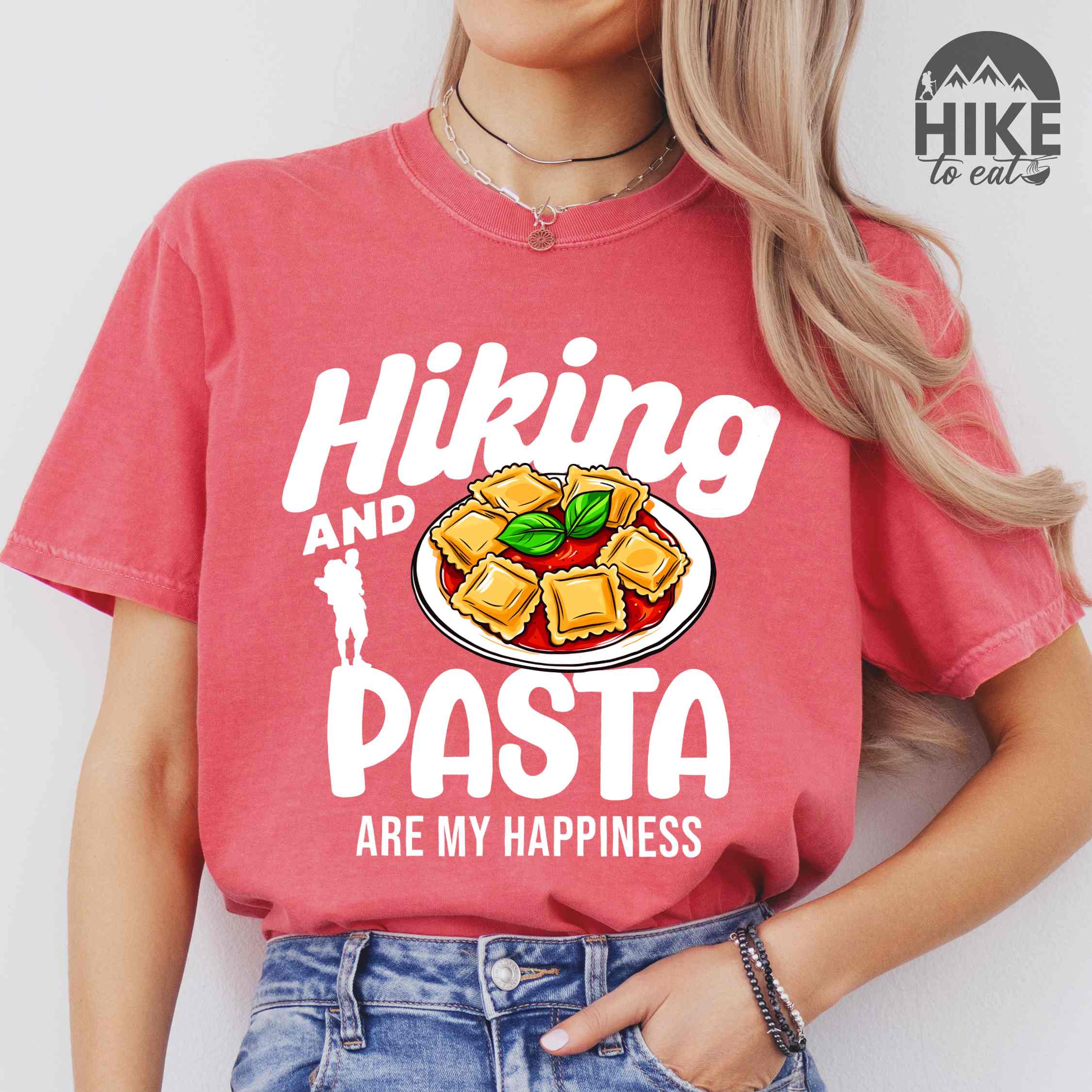 Woman wearing watermelon "Hiking and pasta are my happiness" colored vintage tee with bold typography, illustrated plate of pasta, and backpackers for pasta lovers.