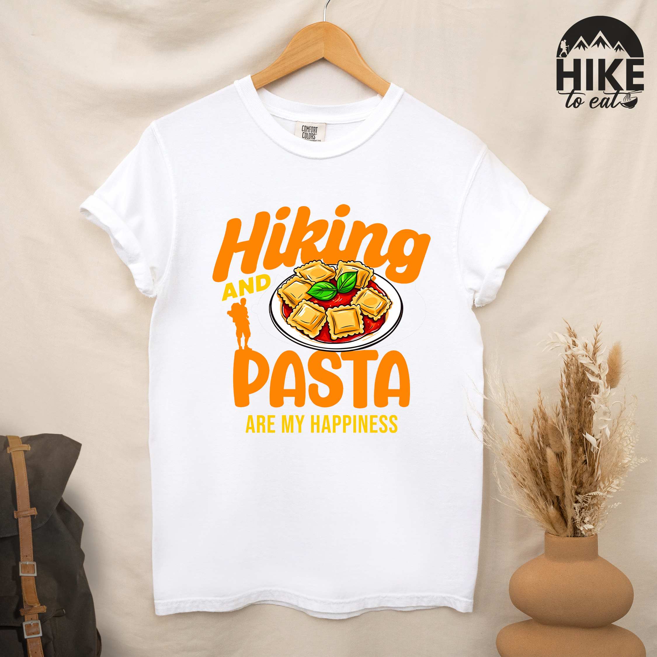 Hanging white "Hiking and pasta are my happiness" colored vintage tee with bold typography, illustrated plate of pasta, and backpackers for pasta lovers.
