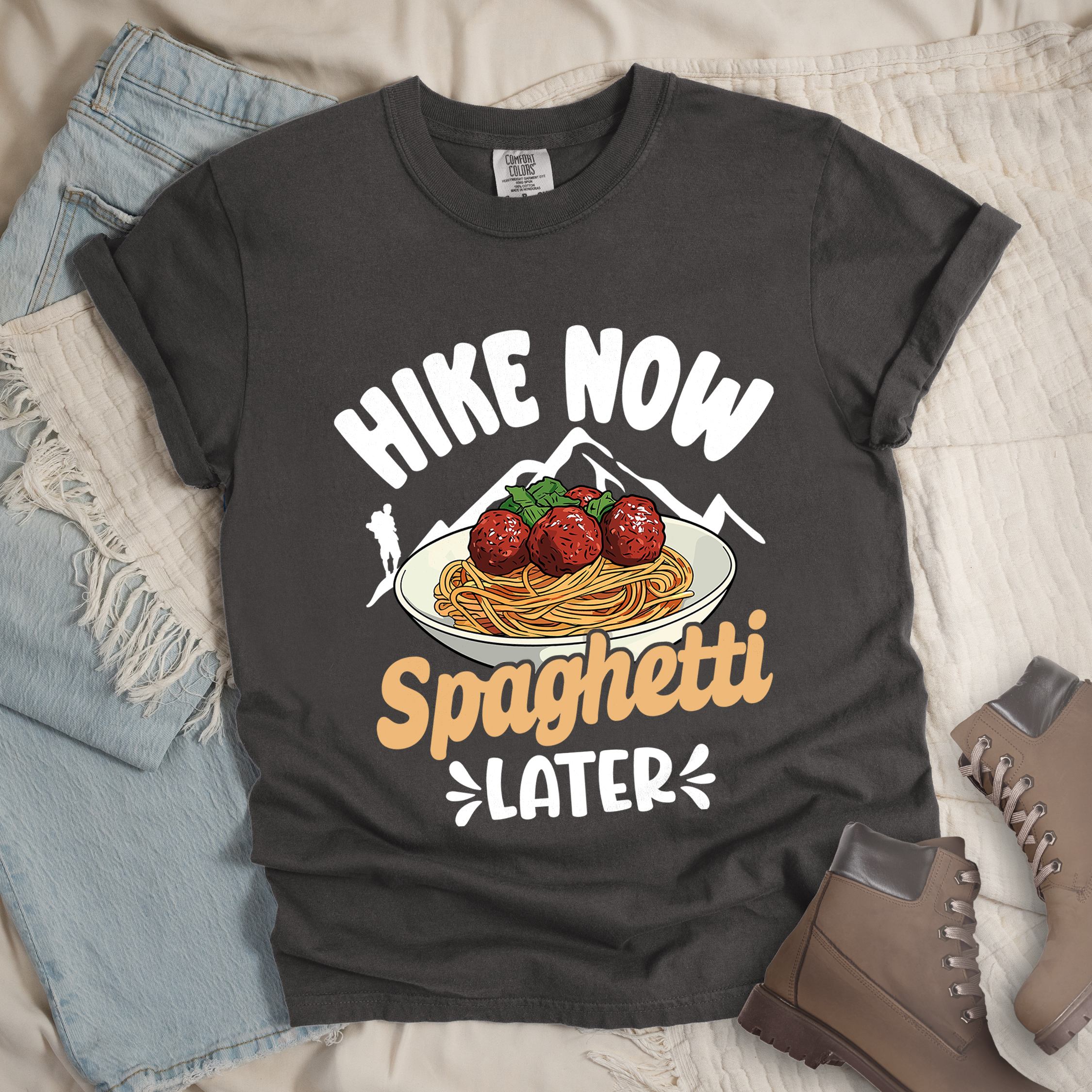 Dark grey shirt with the phrase “Hike Now Spaghetti Later.” Shows a hiker silhouette, mountains, and a plate of spaghetti with meatballs.