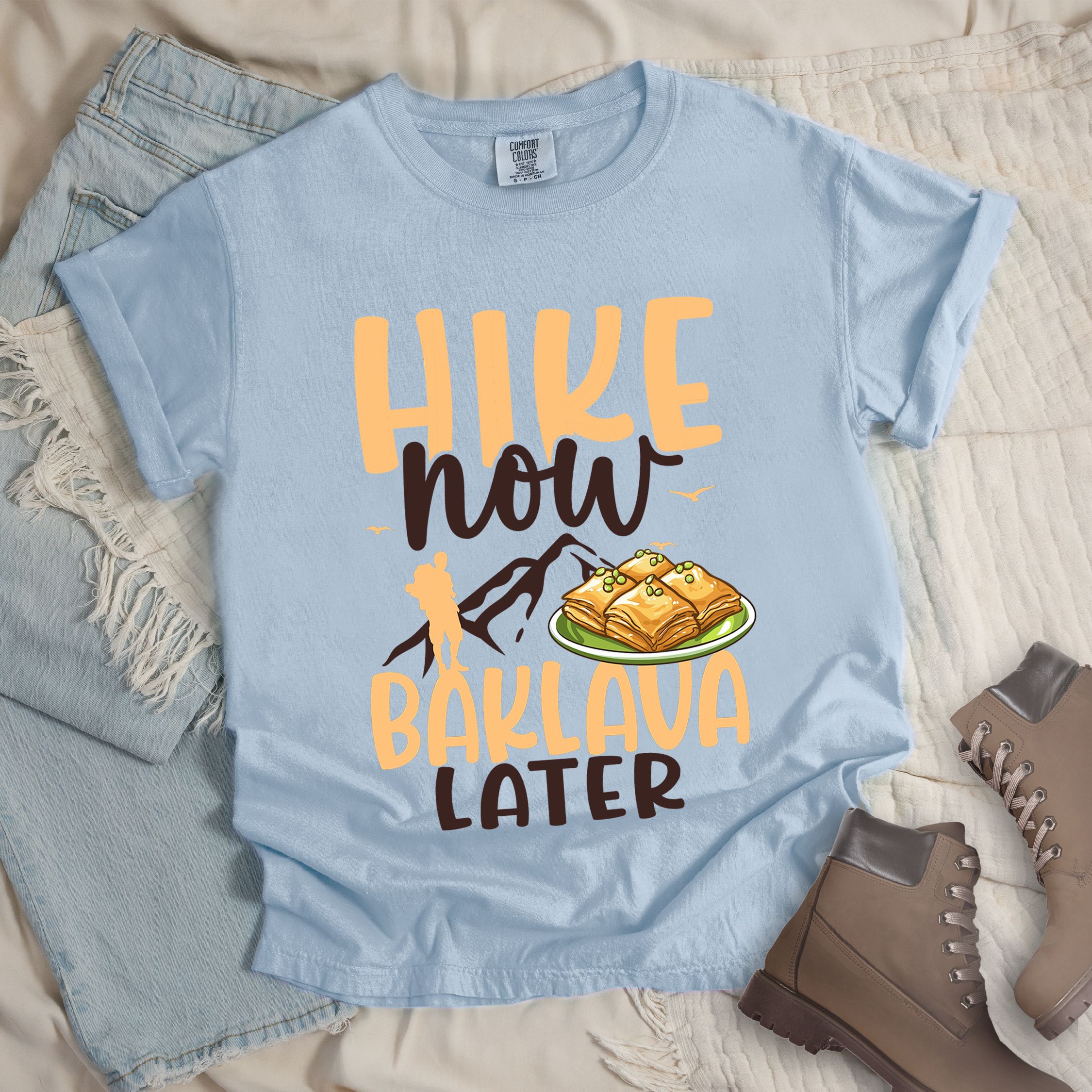 Light blue shirt with Hiking Design featuring the phrase “Will Hike for Baklava” in bold lettering and a colorful illustration of golden baklava on a plate.