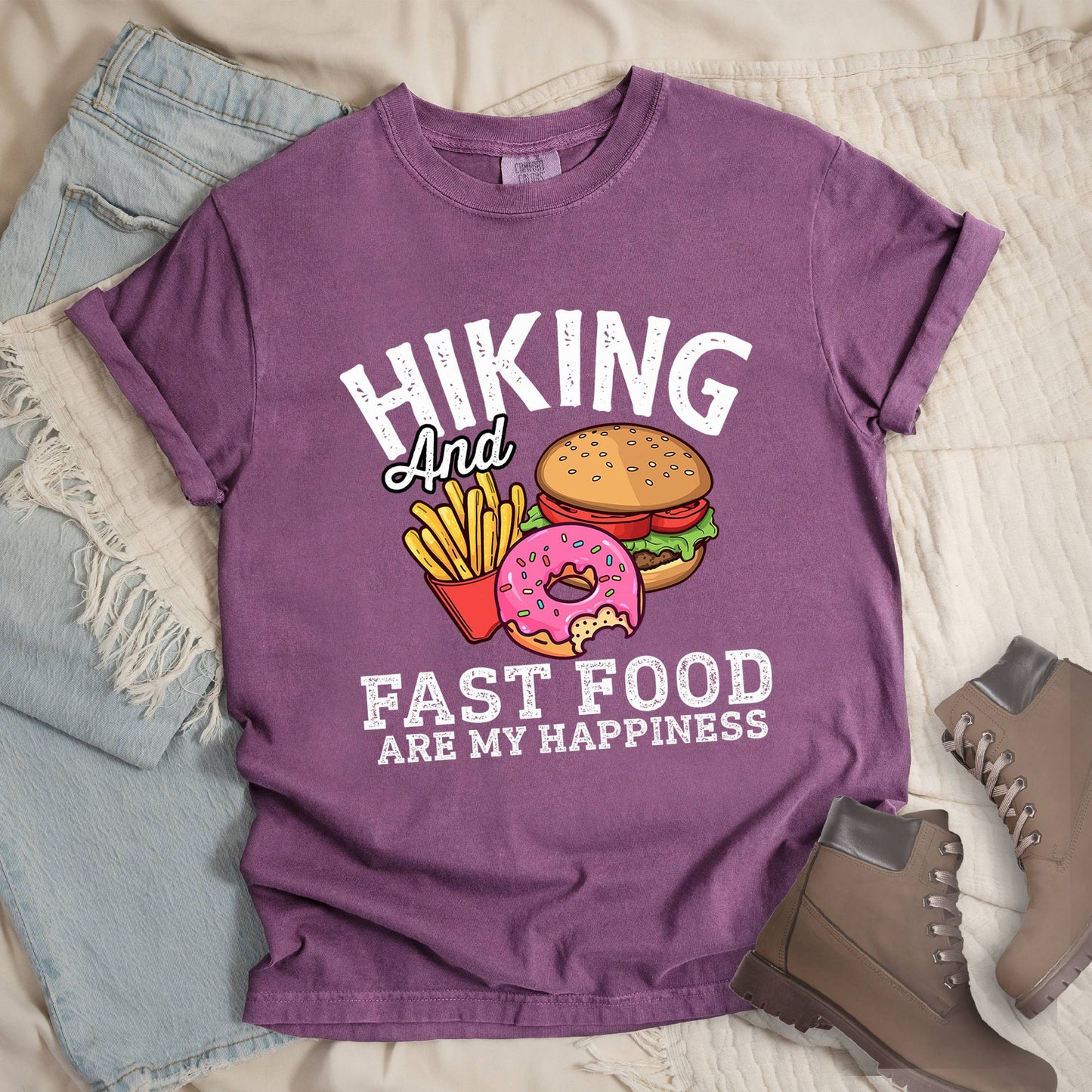 Dark pink shirt showing a hiking design with 'Hiking and fast food are my happiness' phrase and an illustration of fast food meal in front.